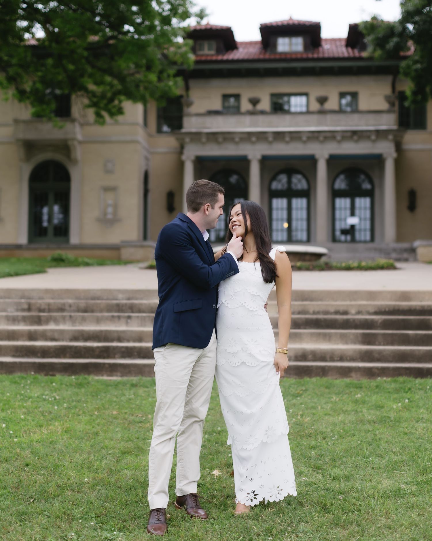 A romantic moment captured on the steps of a stately historic building with classic architecture.