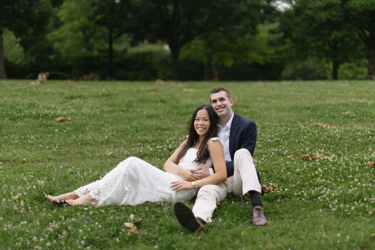 A couple relaxes on a grassy hill during their outdoor photo session.