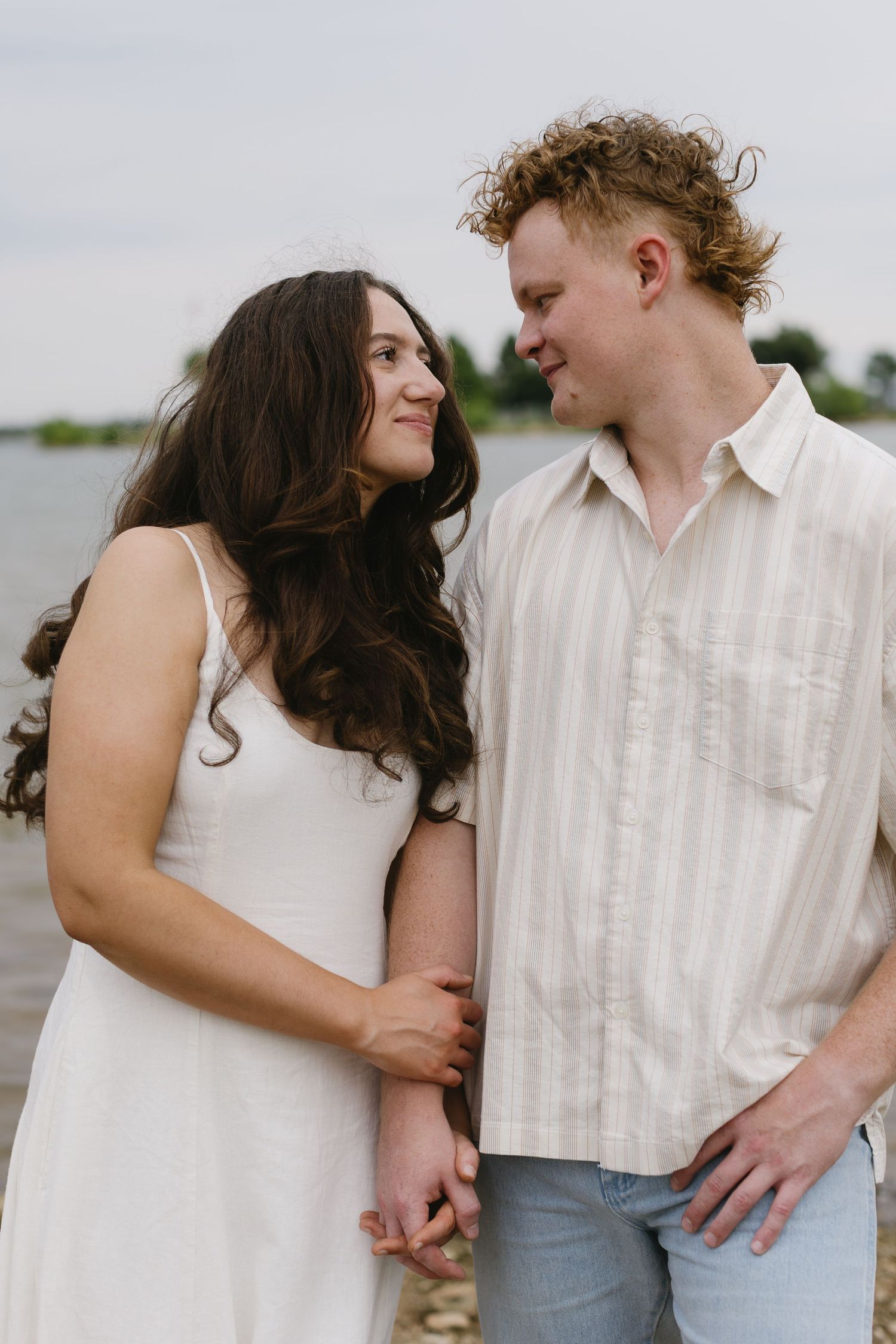 A couple shares intimate moments along a rocky shoreline.