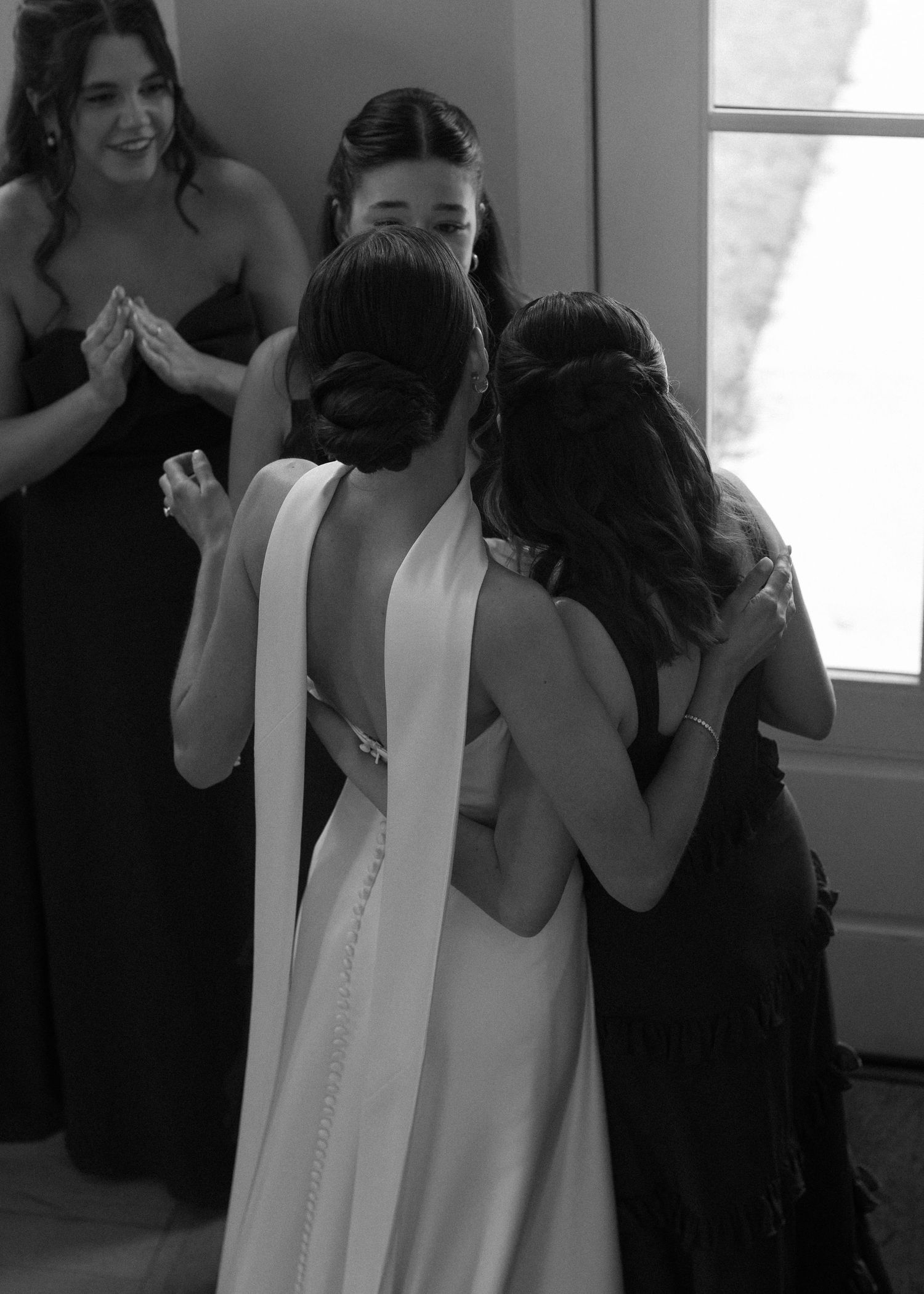 Emotional reactions during a wedding dress fitting with black-clad attendants looking on.