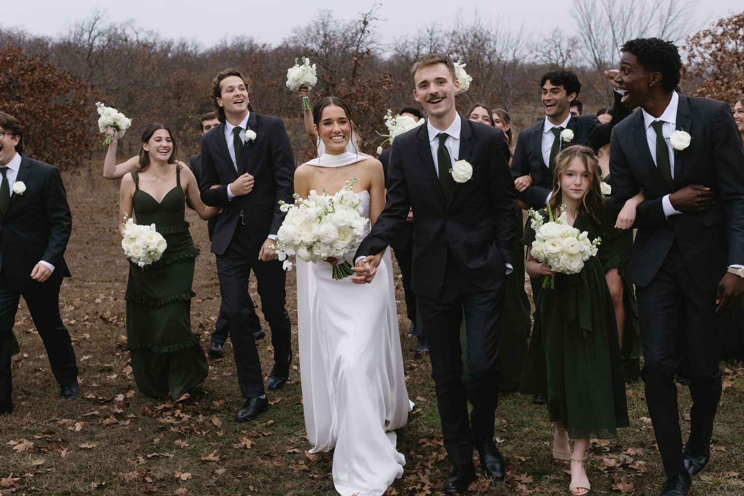 Wedding party in formal attire walking together on a fall day.