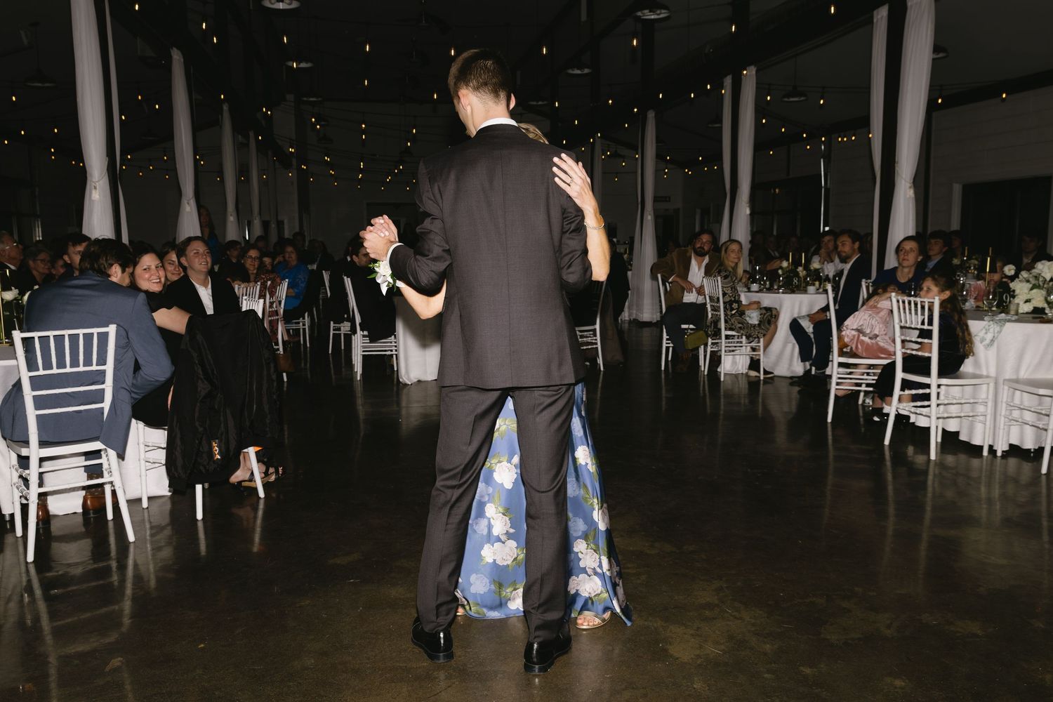 Wedding guests dancing and celebrating on a dark dance floor.