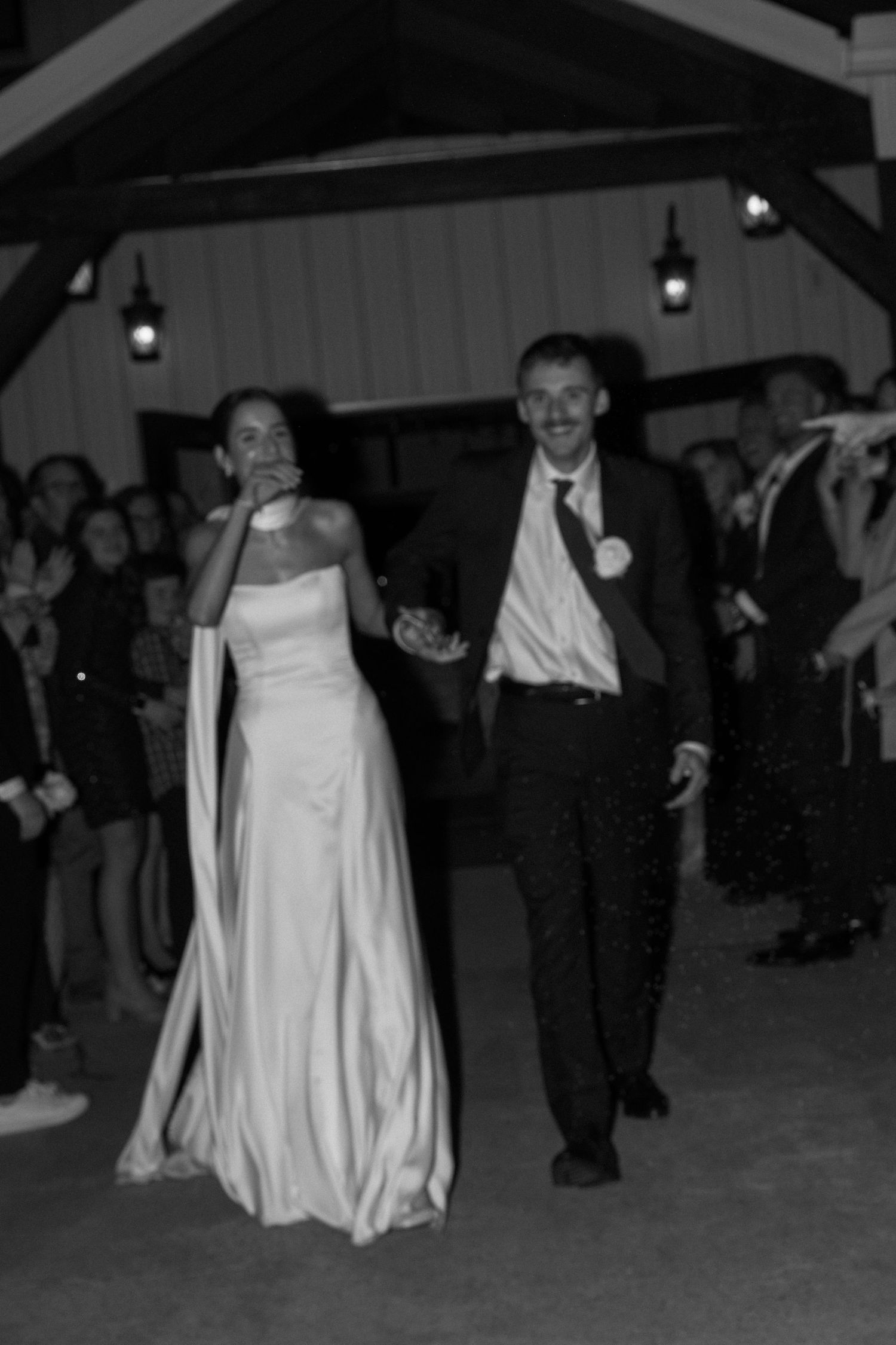 Wedding reception dance floor with couples dancing in formal attire under dim lighting.