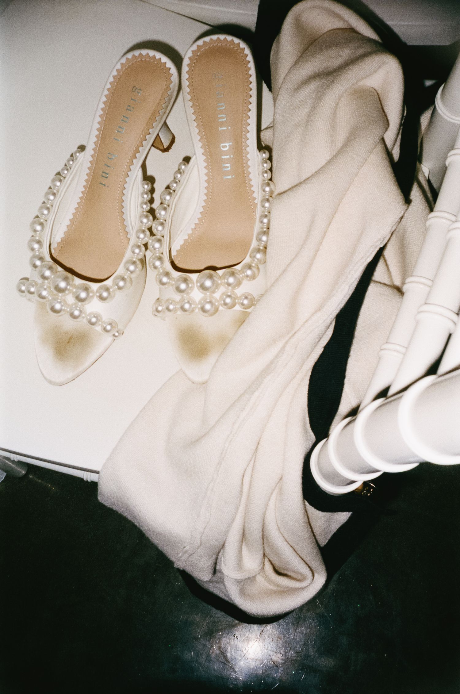 Pearl-embellished wedding shoes laid out on white fabric.