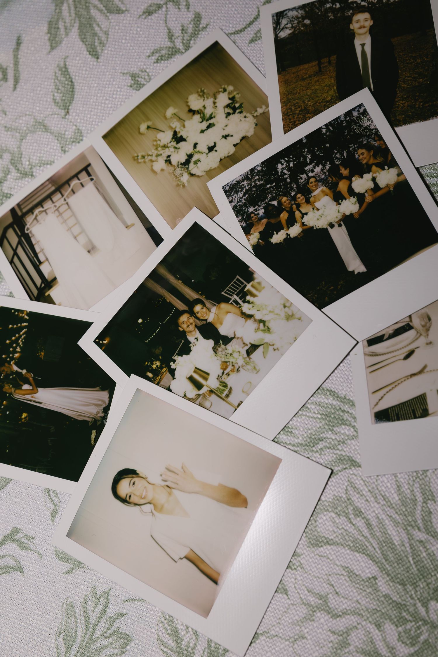 Collection of polaroid wedding photos spread out on a floral patterned surface.