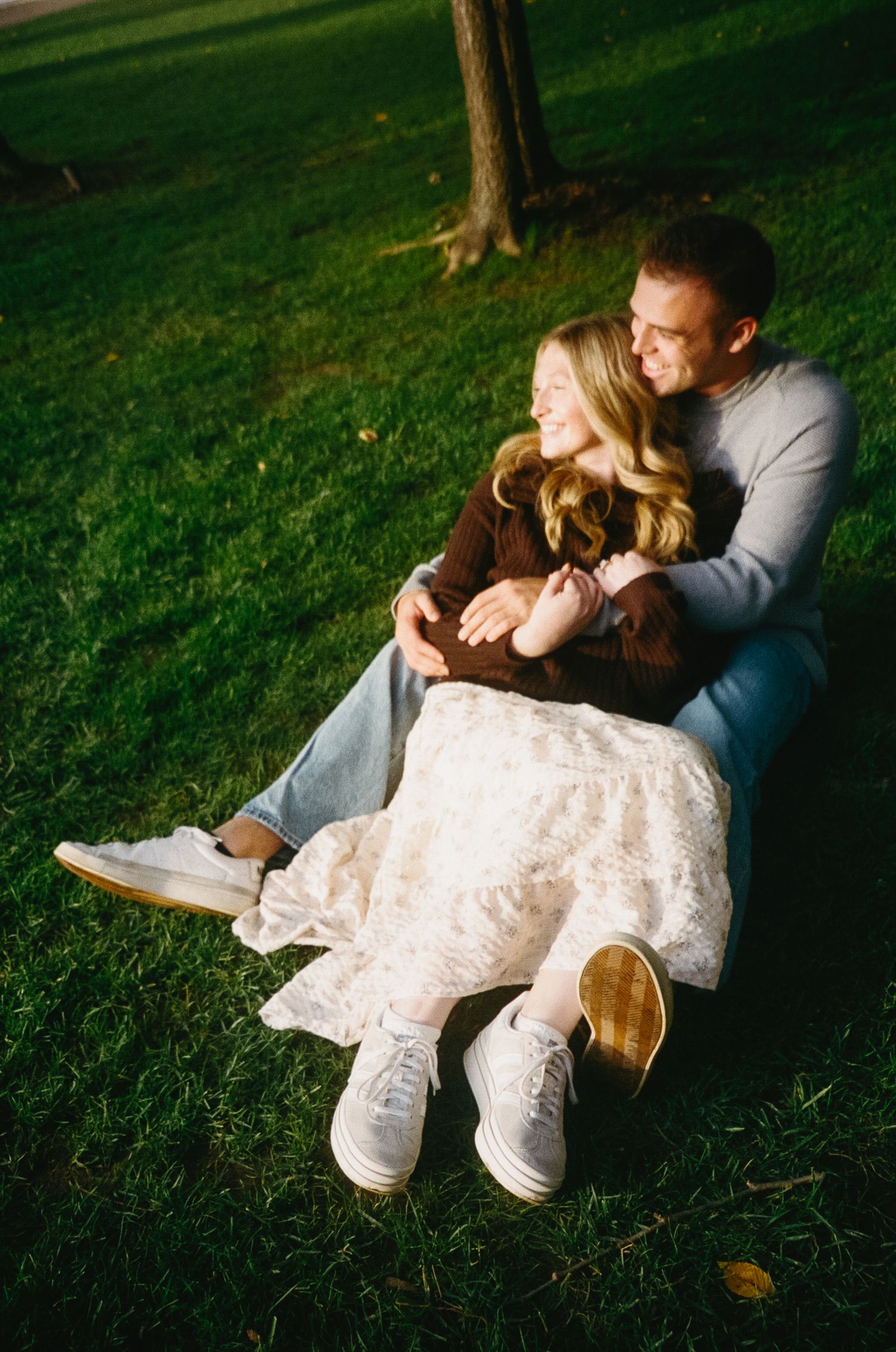 Couple lounging together on green grass during an outdoor photoshoot.