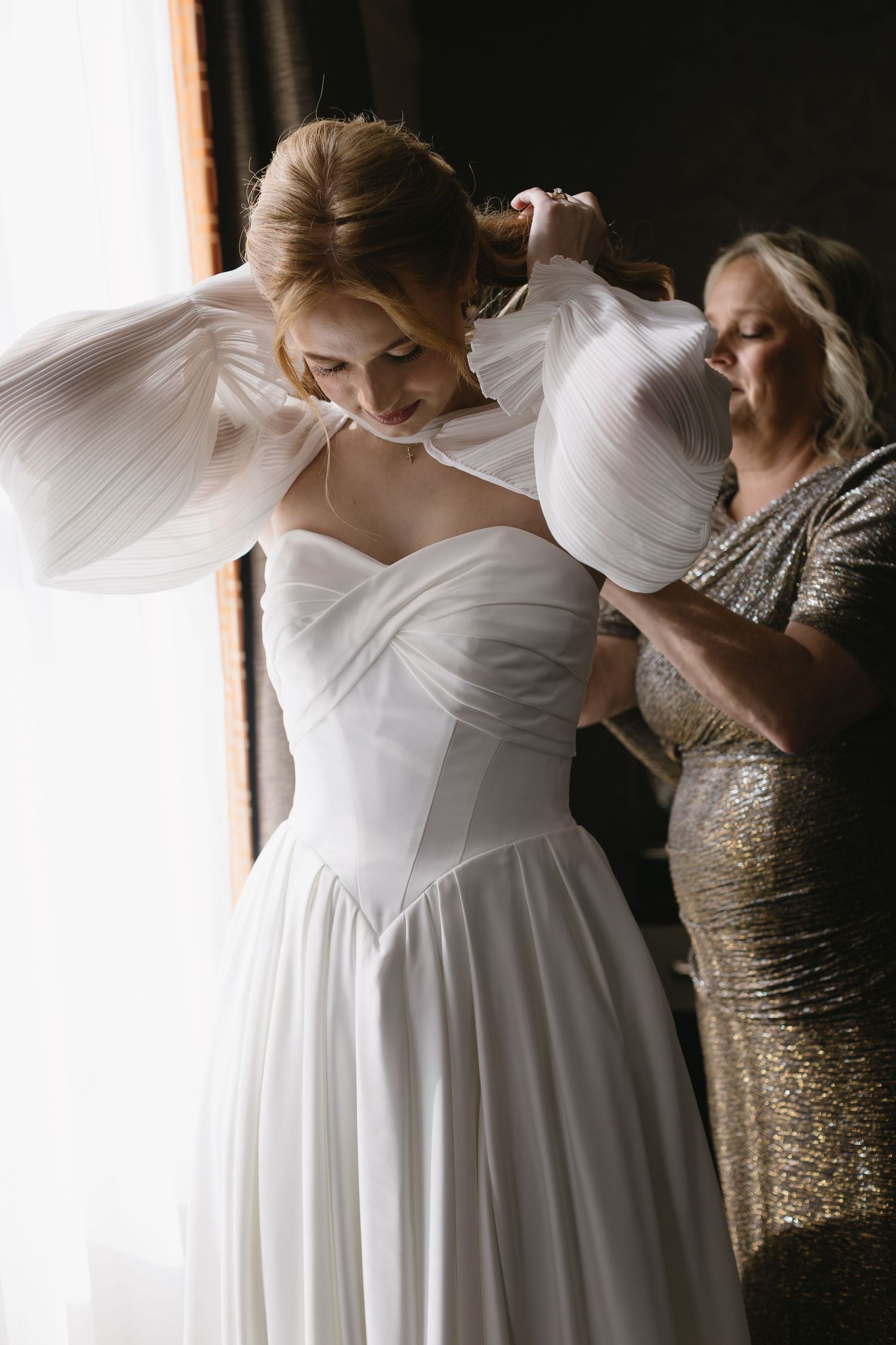 Wedding dress being fitted with gold sequined dress visible in background.