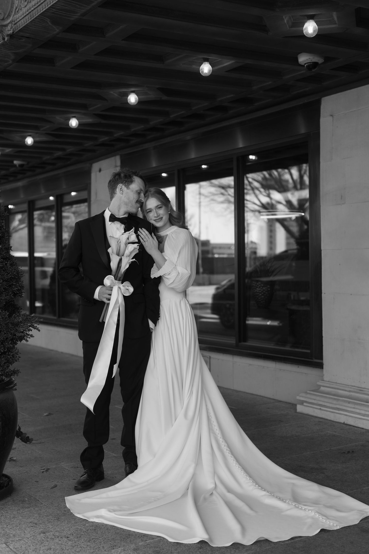 Romantic wedding portraits under covered walkway with dramatic train of white gown.