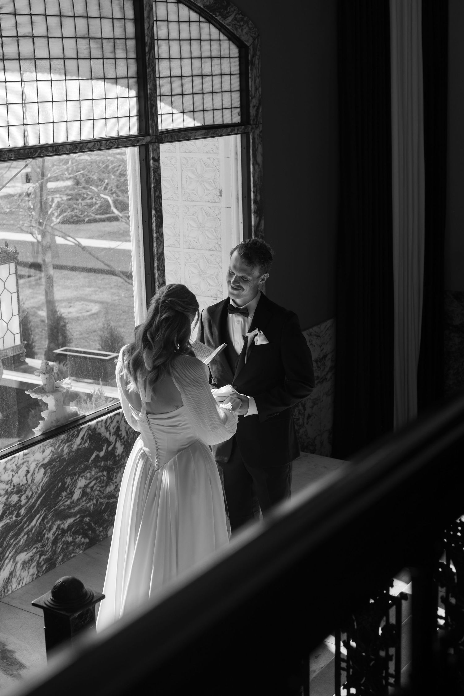 Black and white wedding photos showing intimate moments by a window.