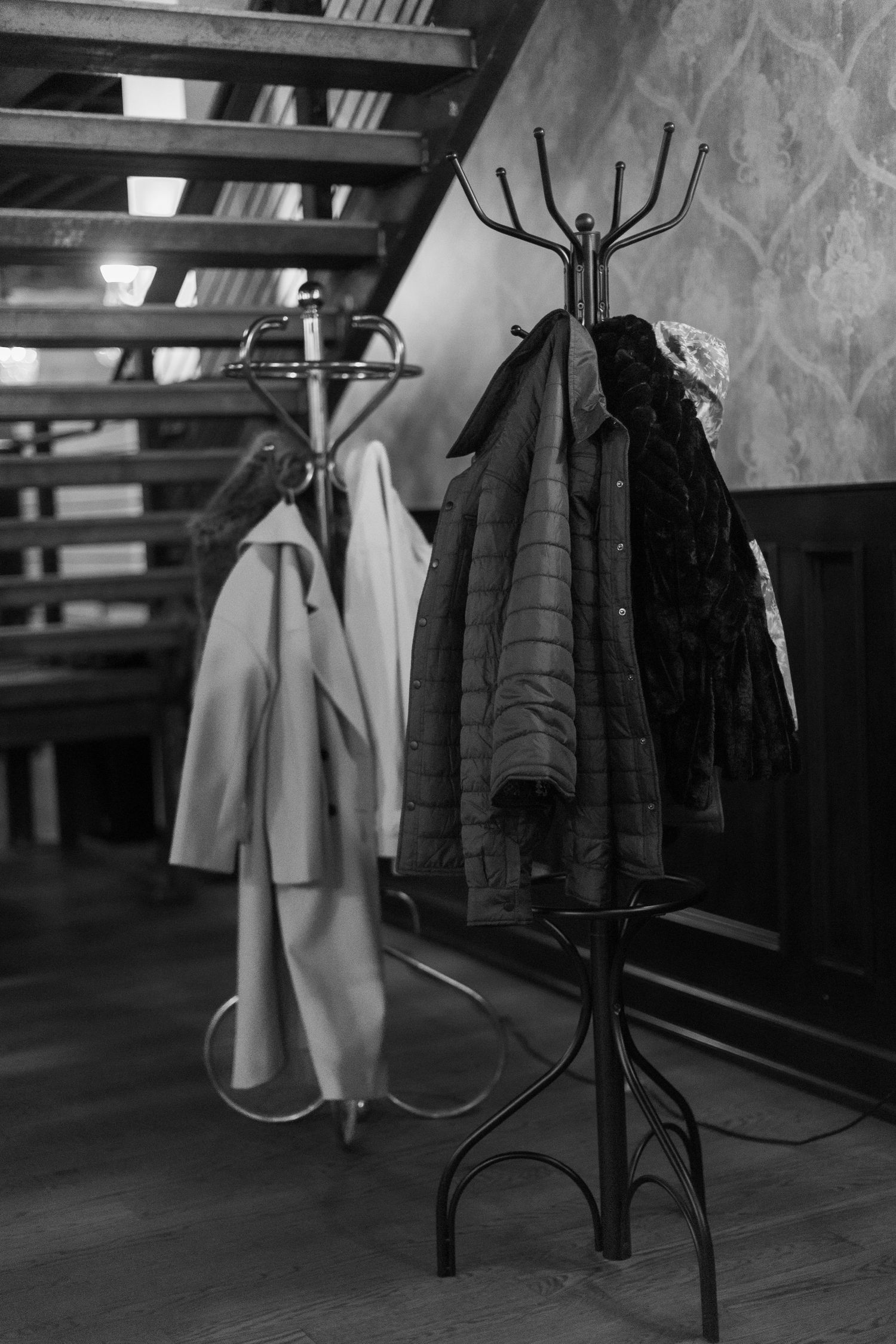 Coat rack with winter jackets and coats hanging in a dimly lit venue space.
