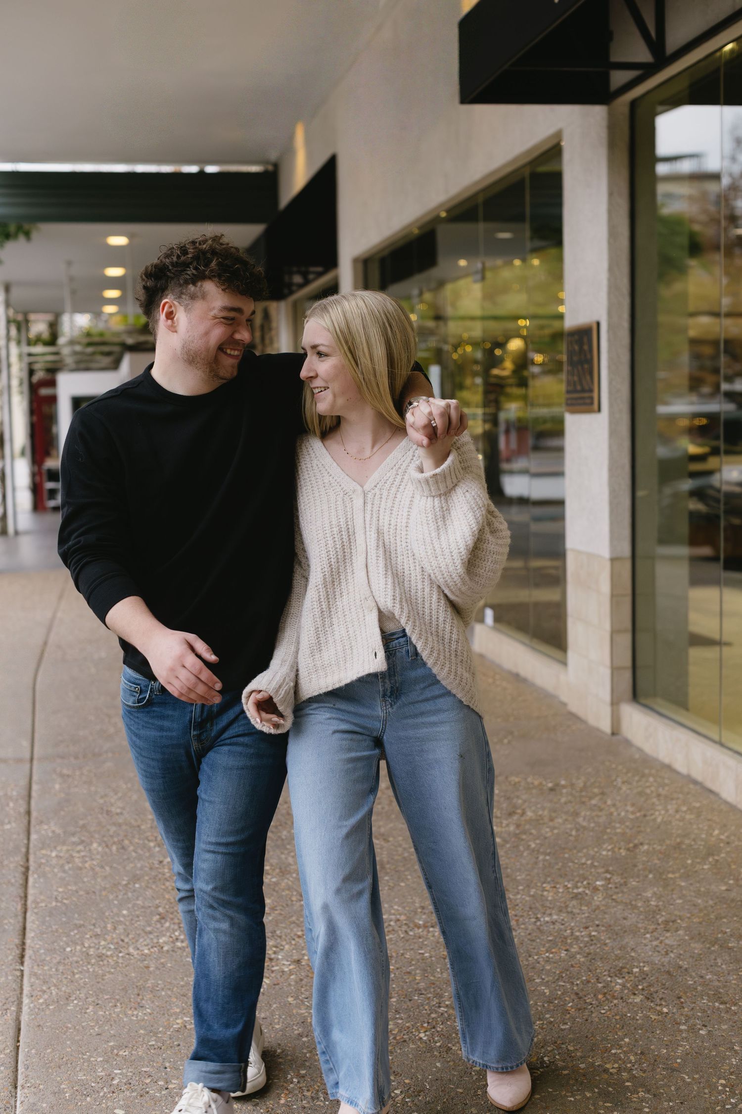 Couple walking together in a covered walkway wearing complementary casual attire.
