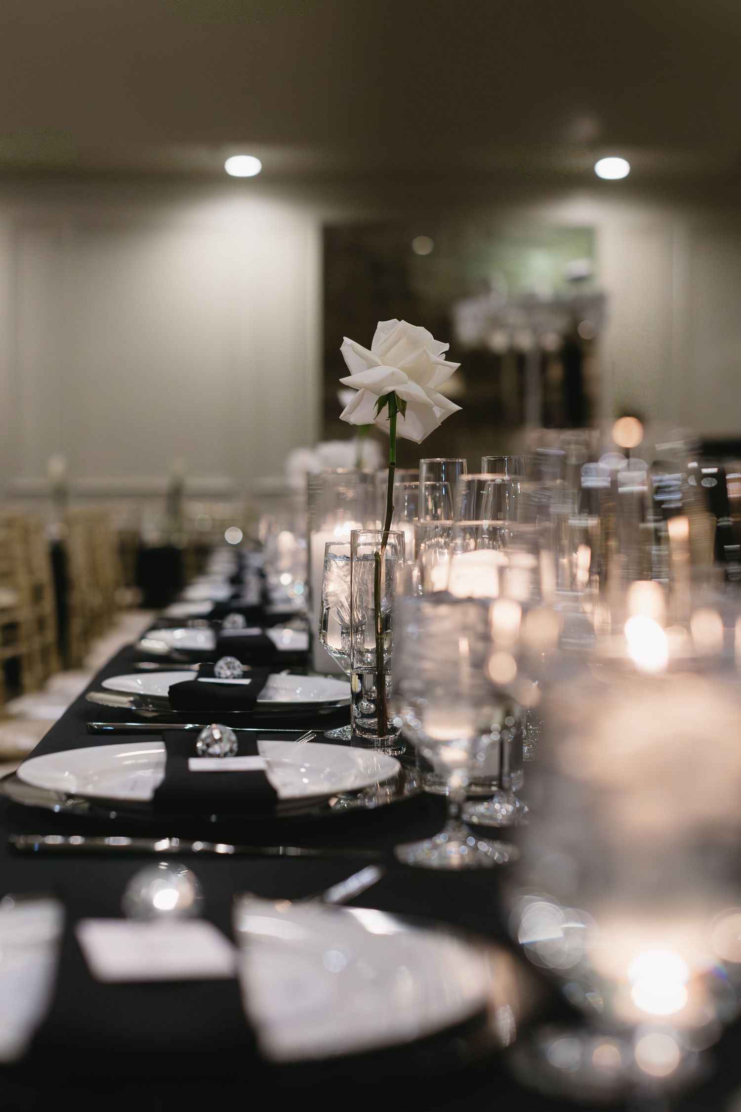 Elegant wedding reception table settings with black linens and candlelight.