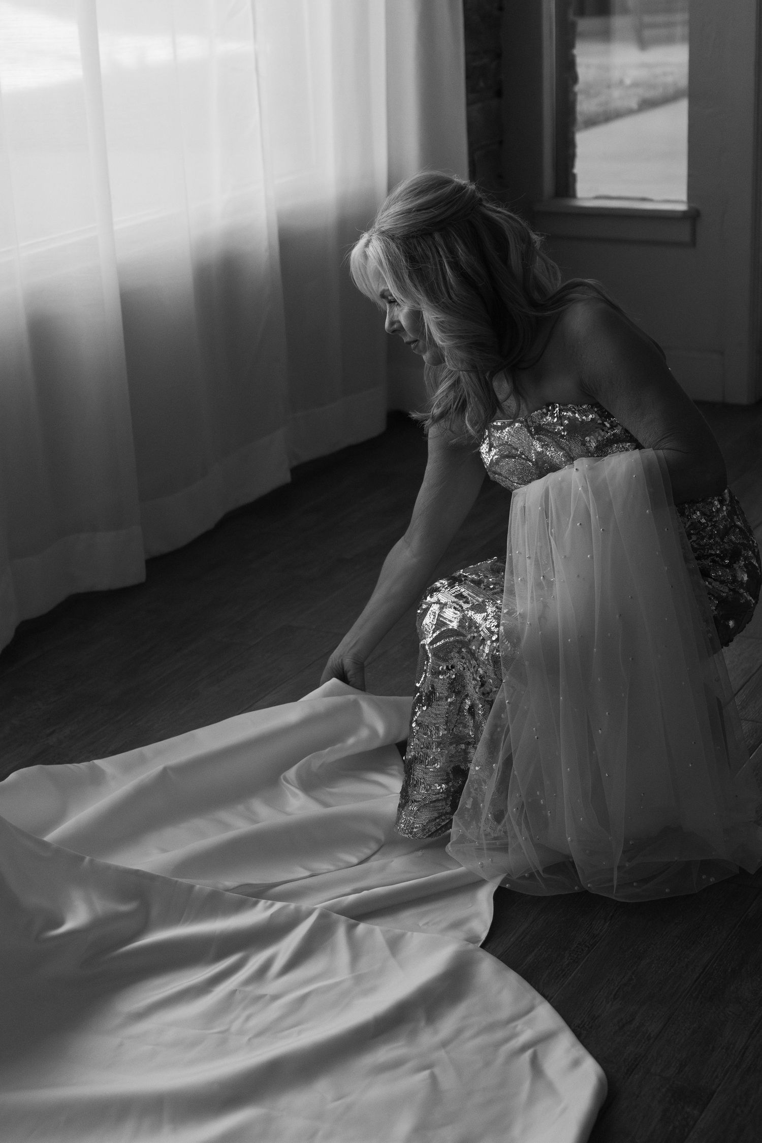 Black and white photo of a wedding dress being steamed and prepared on the floor.