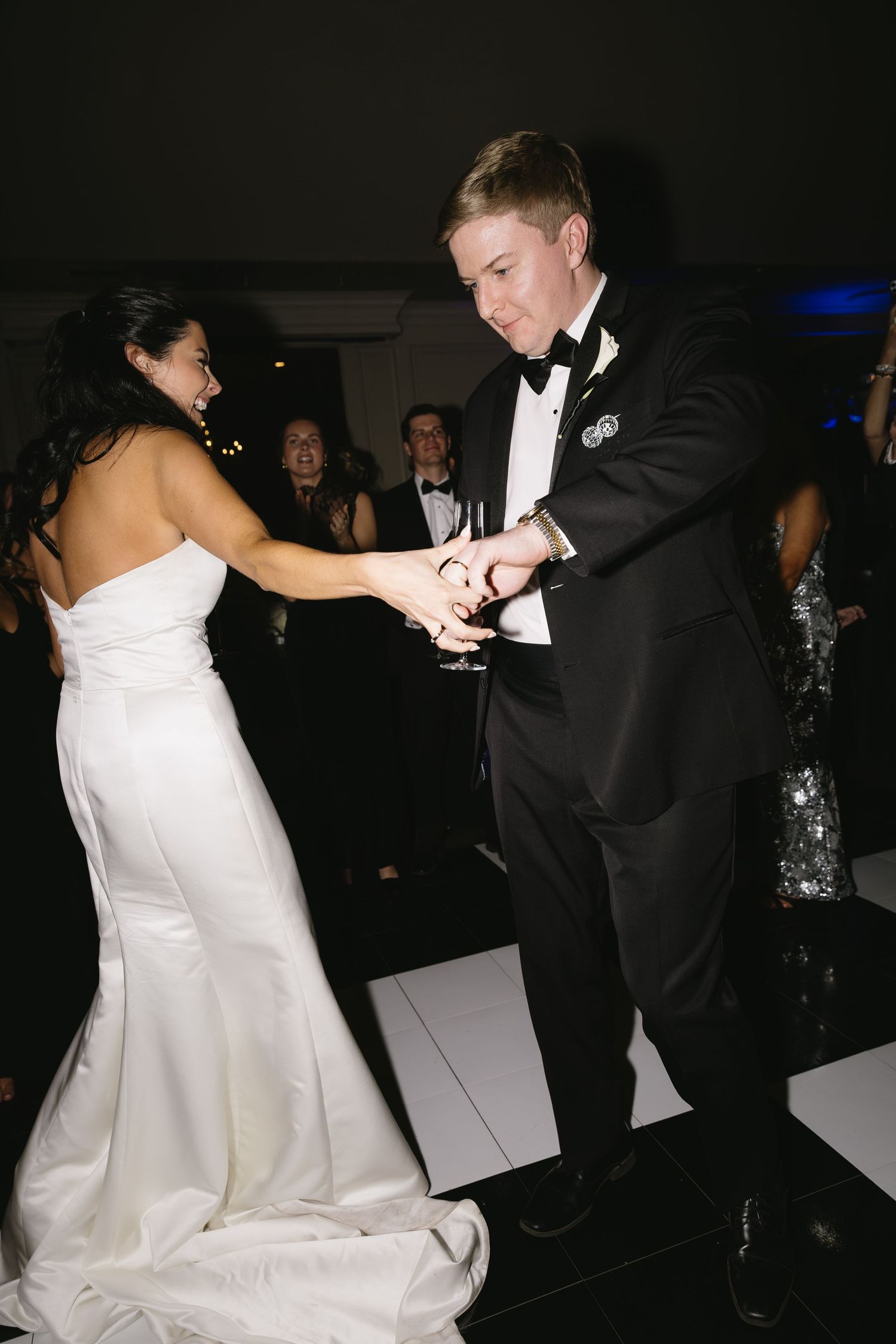 Wedding couple dancing energetically on white dance floor during evening reception.