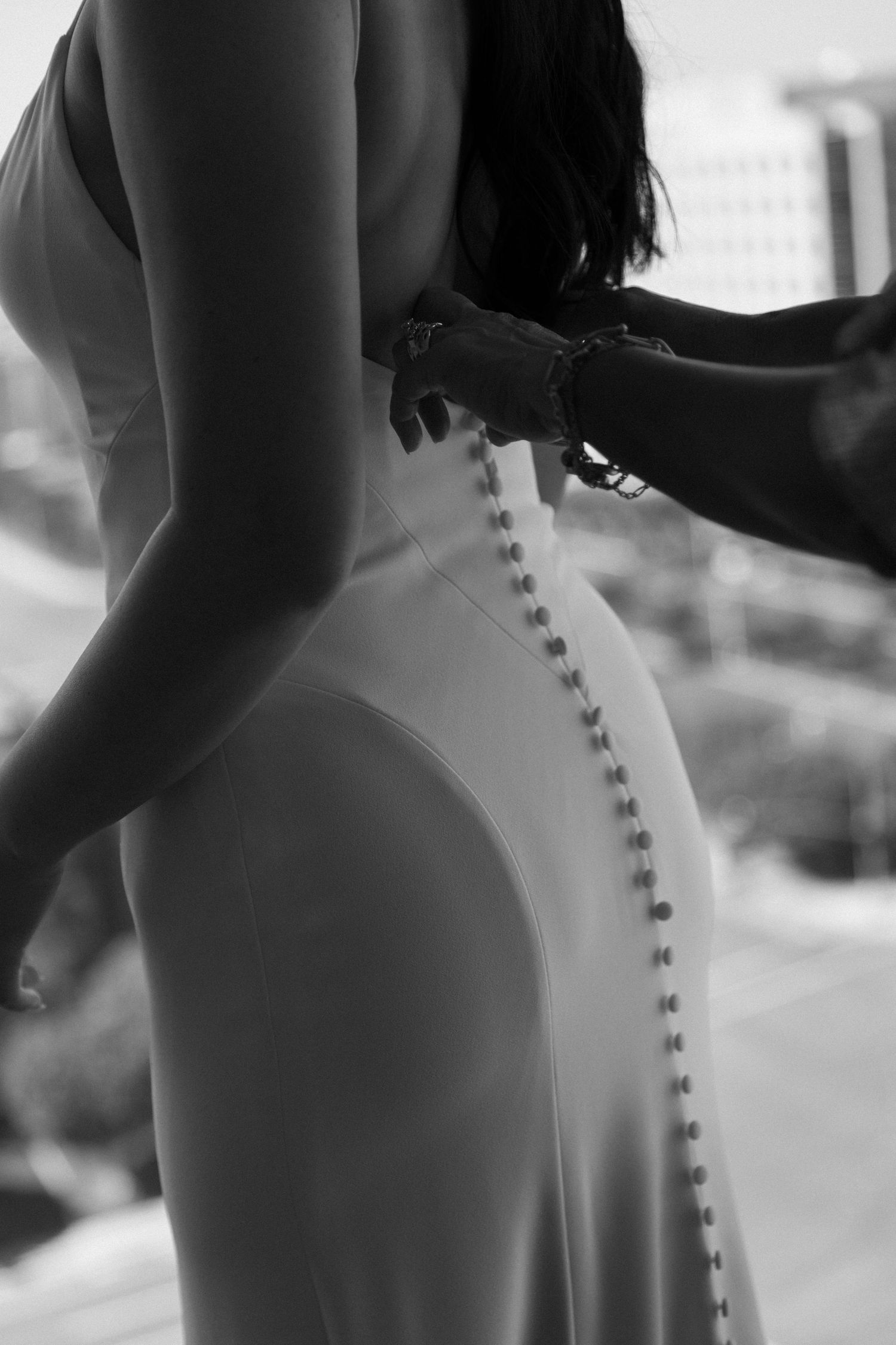 Close-up details of a white wedding dress with delicate button closures along the back.