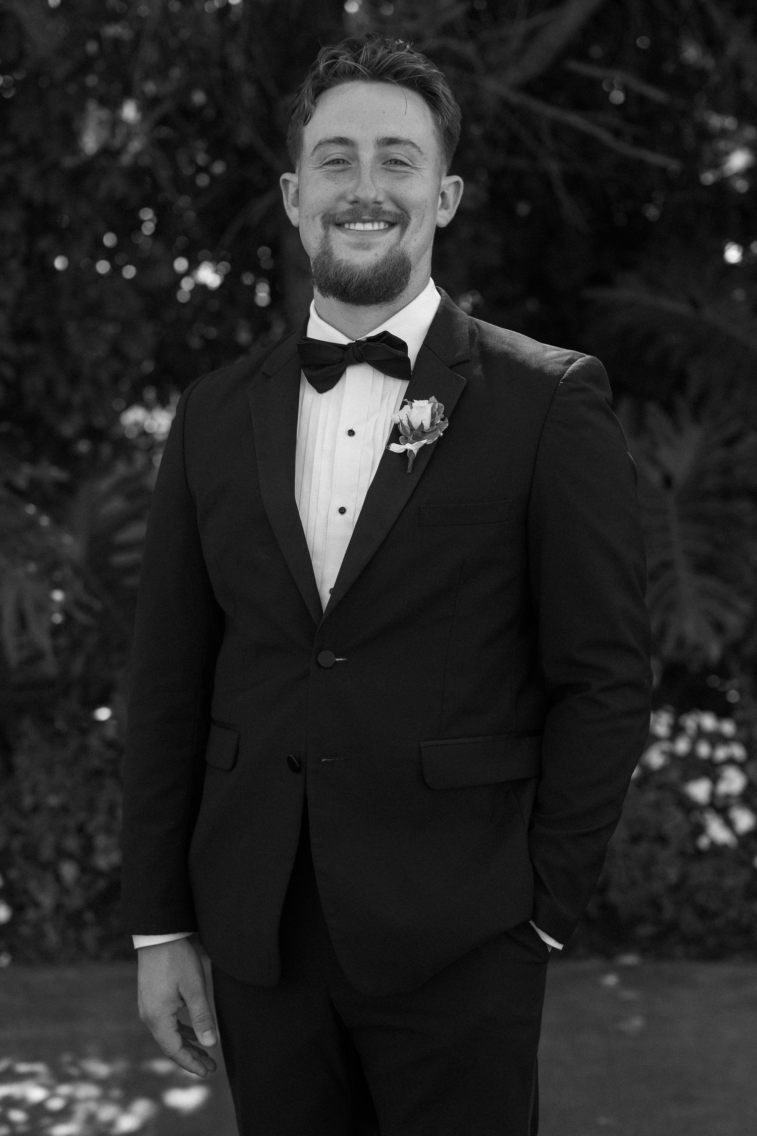 Groomsmen in classic black tuxedos share joyful moments during outdoor wedding photography.