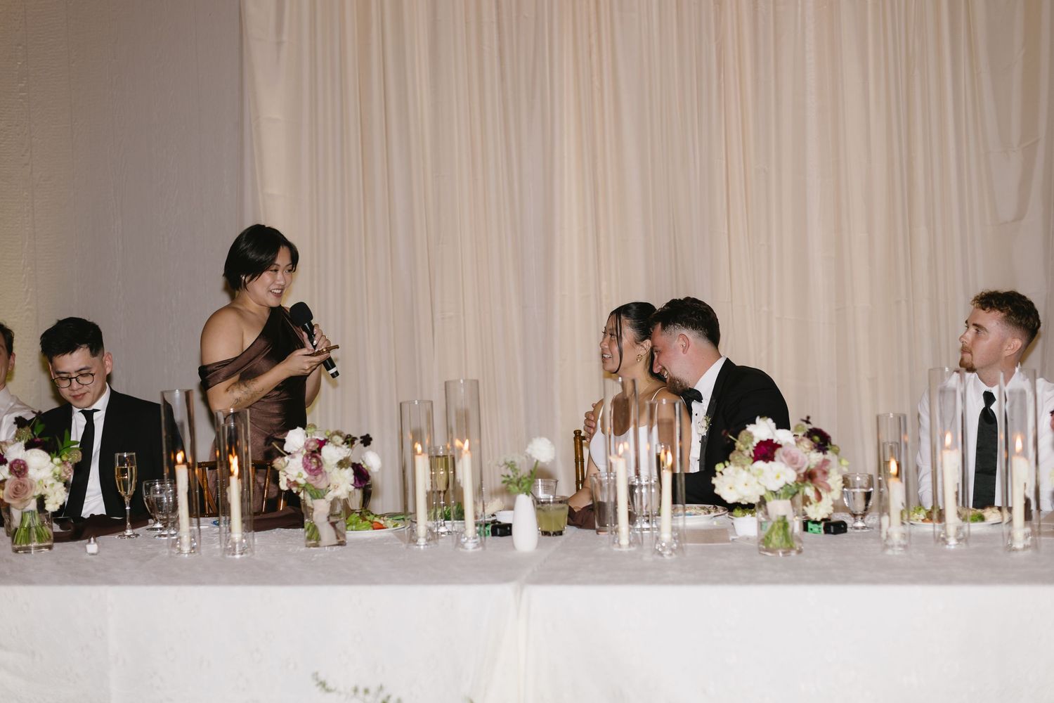 Elegant wedding reception setup with white draping and table settings.
