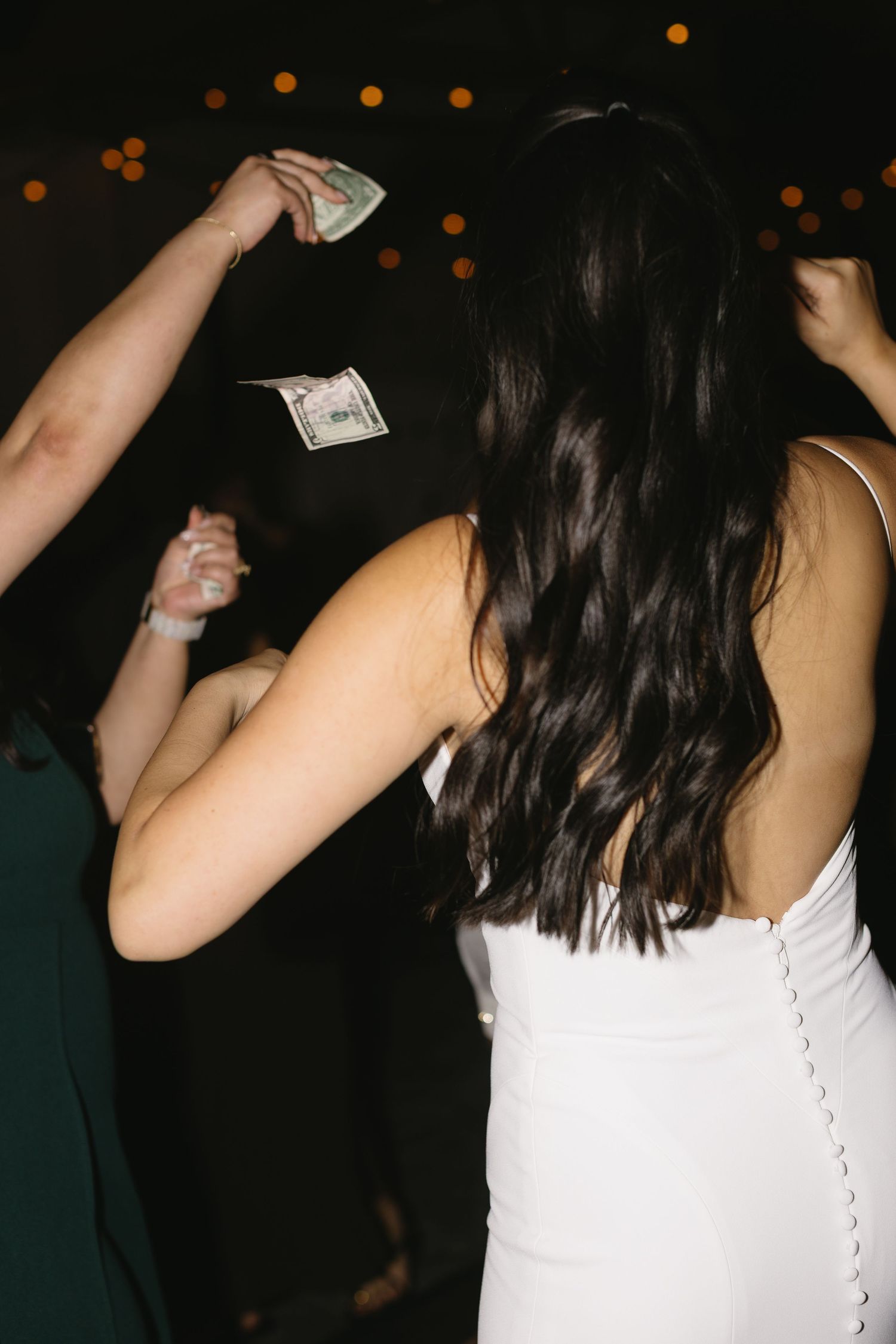 Reception celebration scene with dancing in white dress against dark background with glowing lights.