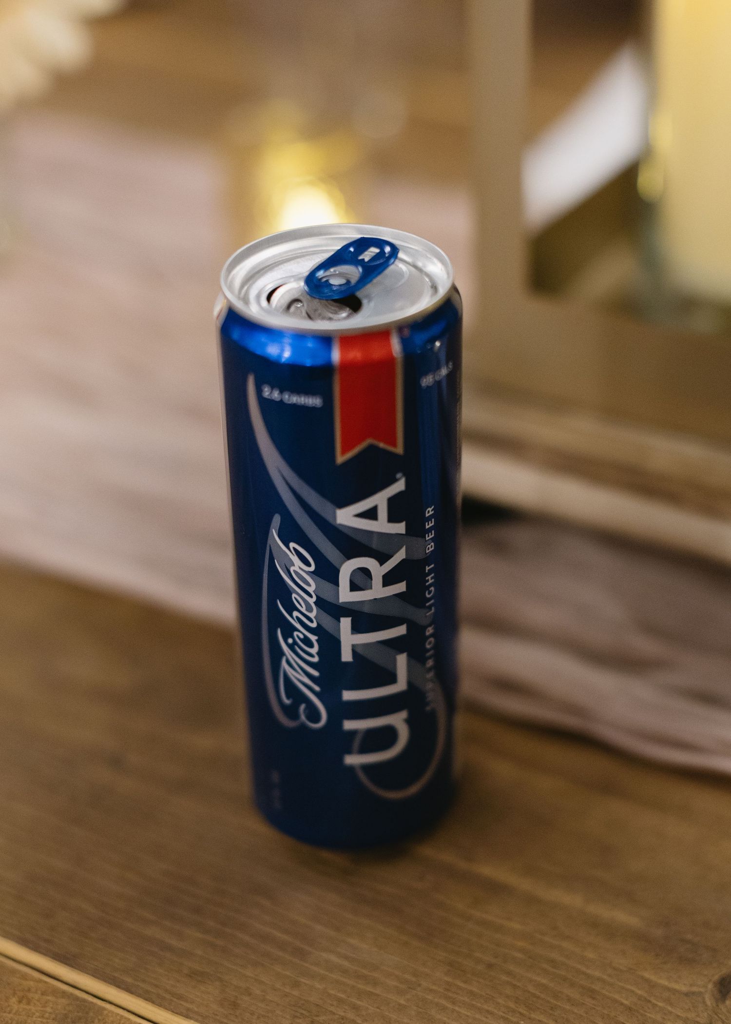 Multiple Michelob Ultra beer cans arranged on a wooden table surface.