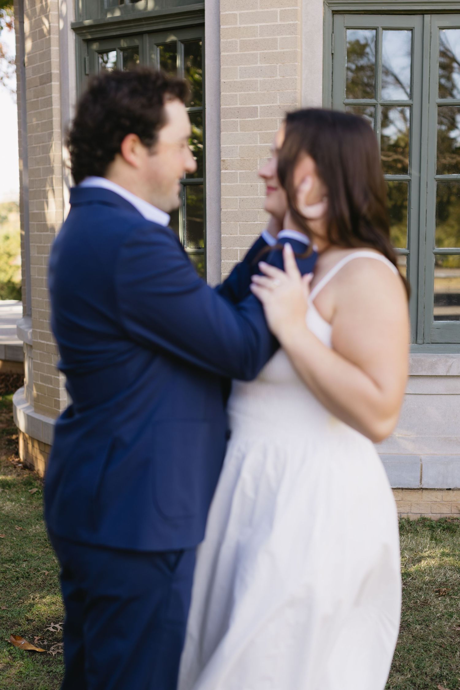 A couple dancing and laughing together outside a brick building.