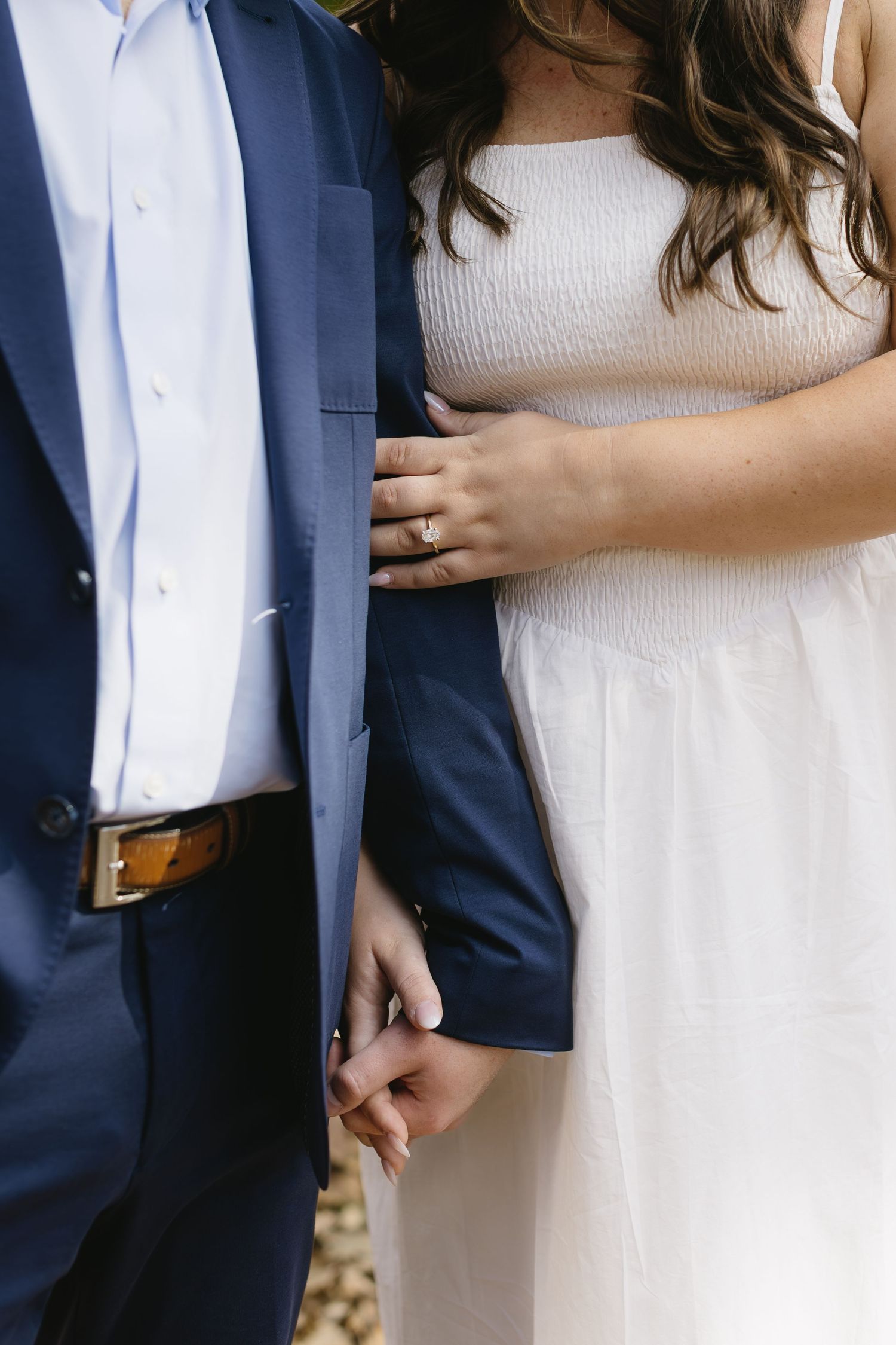 Close-up detail shots of couple in white dress and navy blazer showing tender moments.