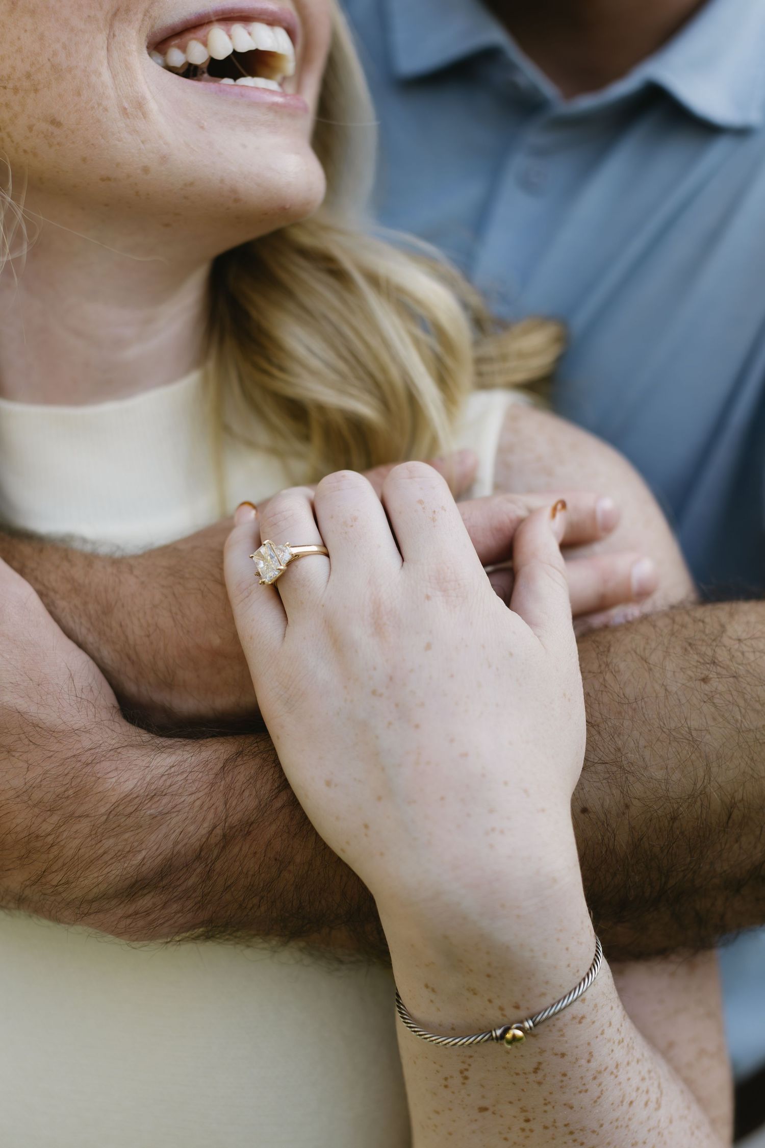 A close-up shot showing hands embracing and a diamond engagement ring.