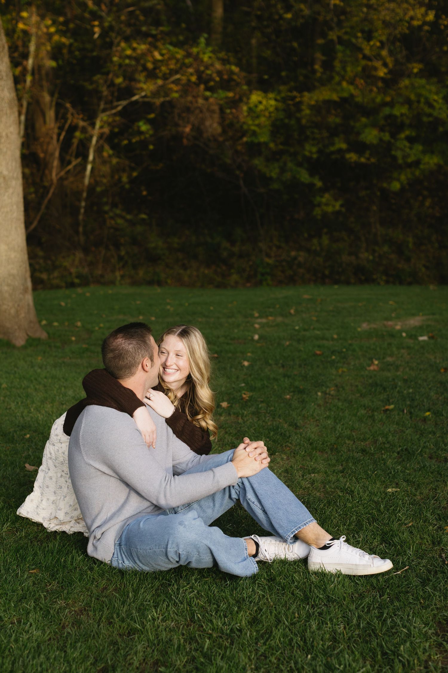 Couple relaxing together on grass in park during autumn photoshoot.