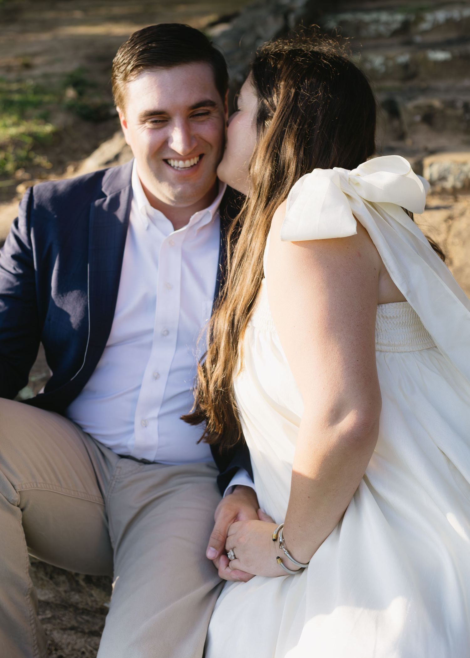 Couple in wedding attire sitting together and sharing intimate moments on steps outdoors.