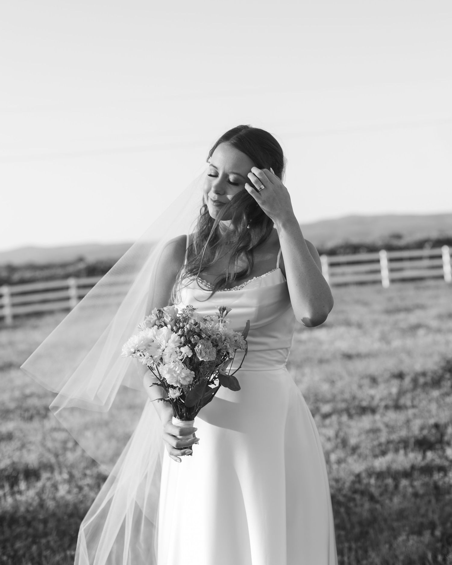 A joyful bridal moment captured in black and white with a bouquet and flowing veil.