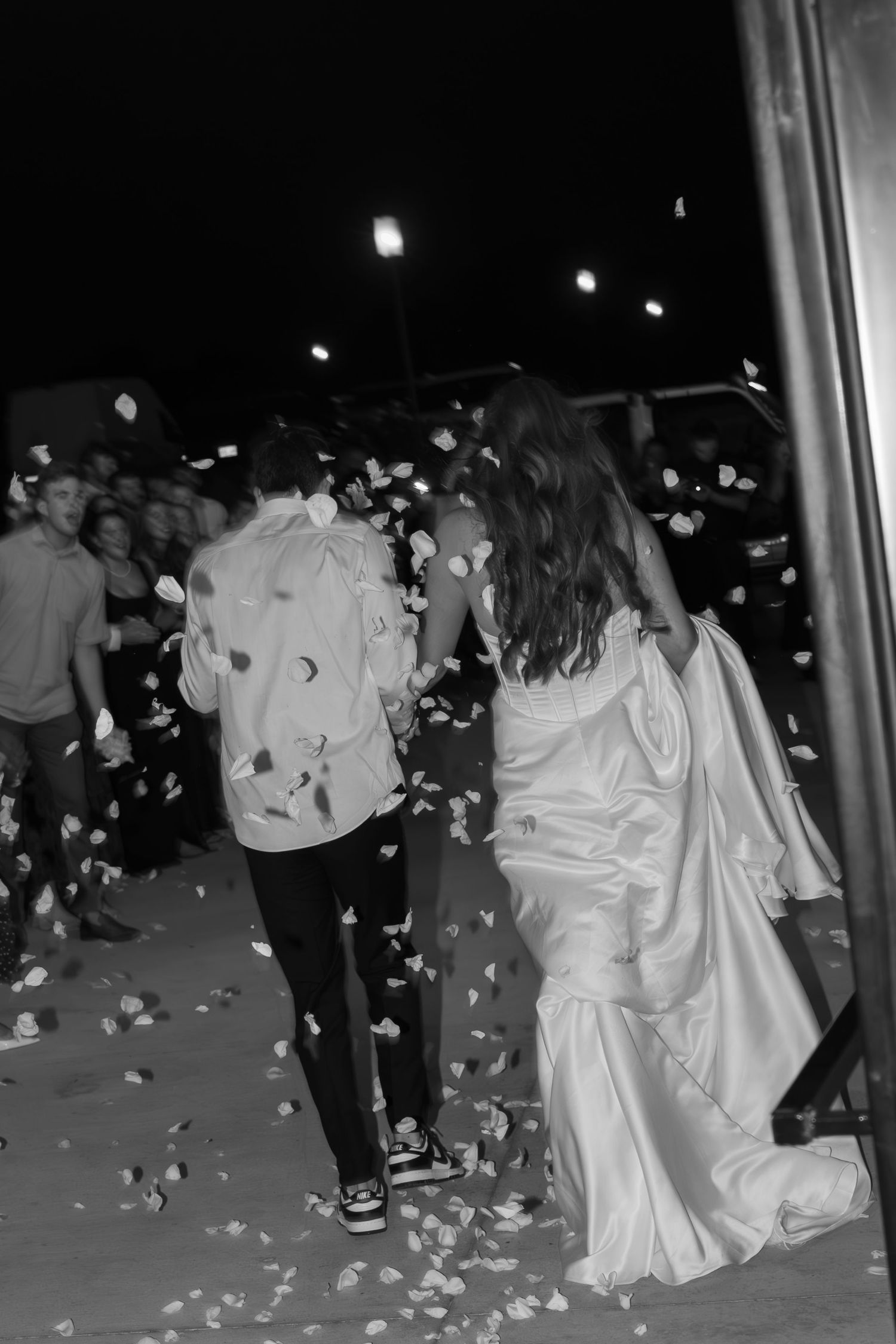 Nighttime celebration with flower petals being thrown at wedding reception.