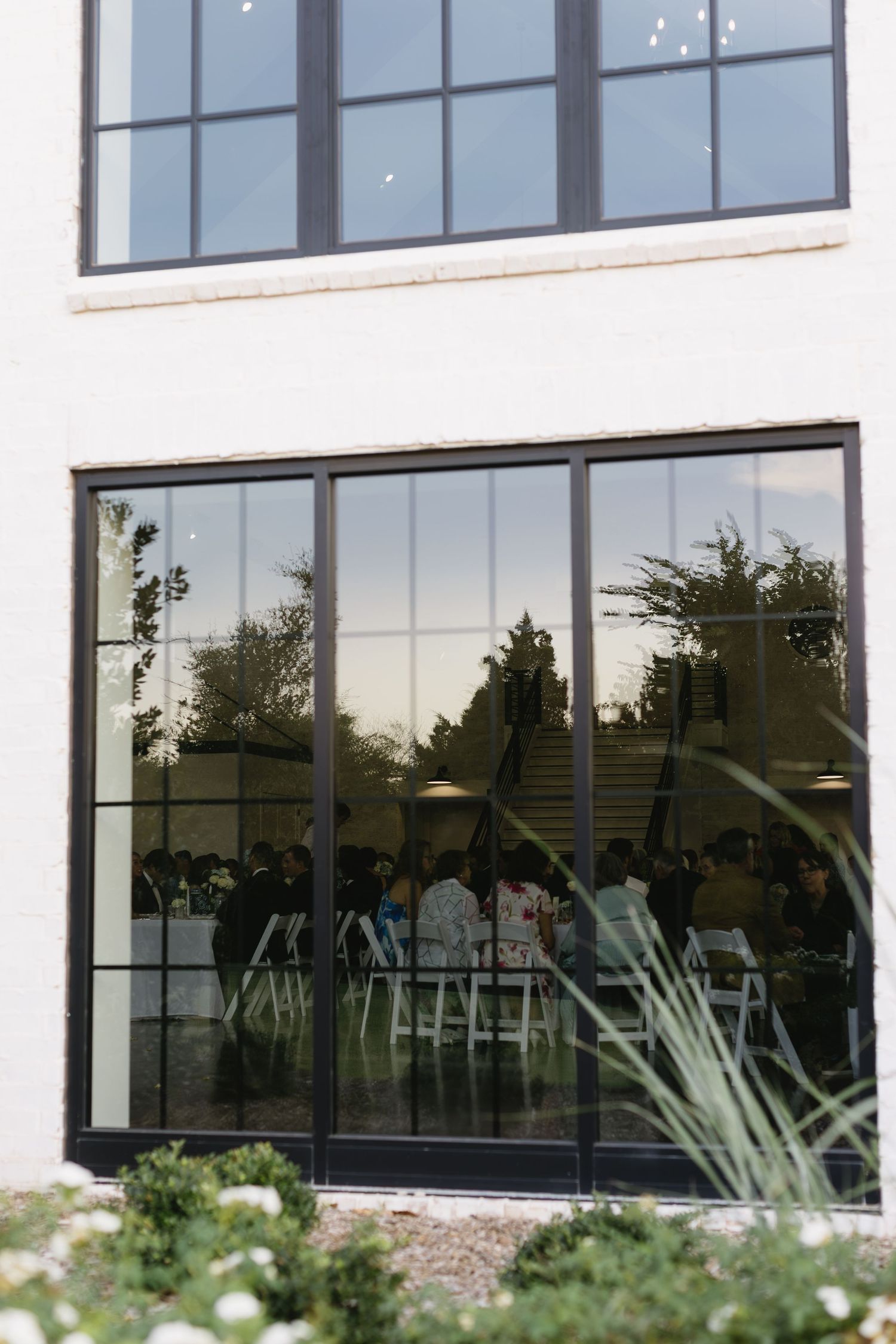 Large windows of a modern wedding venue with white exterior and landscaping.