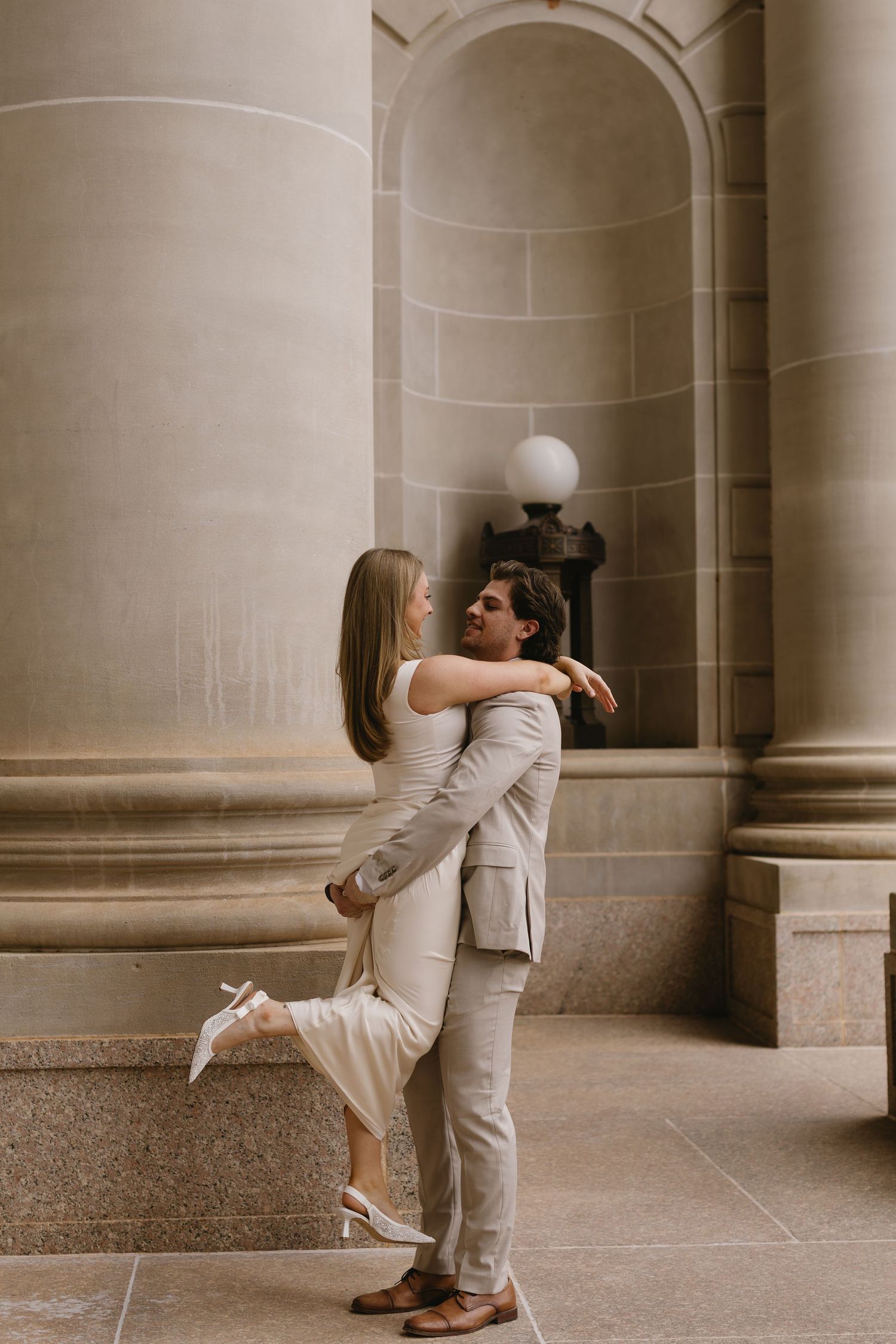 A romantic sequence shows a couple in light formal wear embracing near classical architecture.
