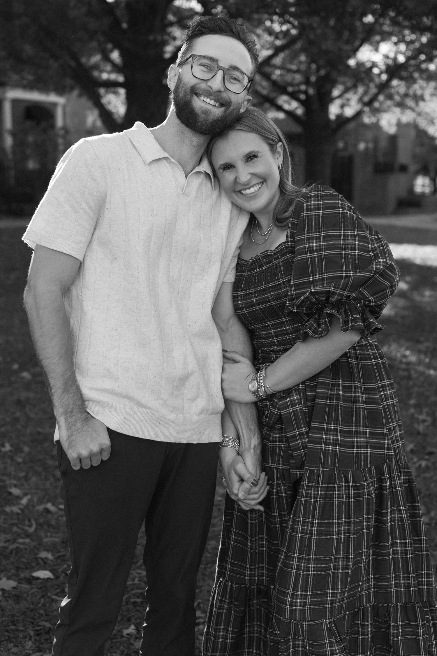 A couple and their white dog share affectionate moments in a series of black and white outdoor portraits.