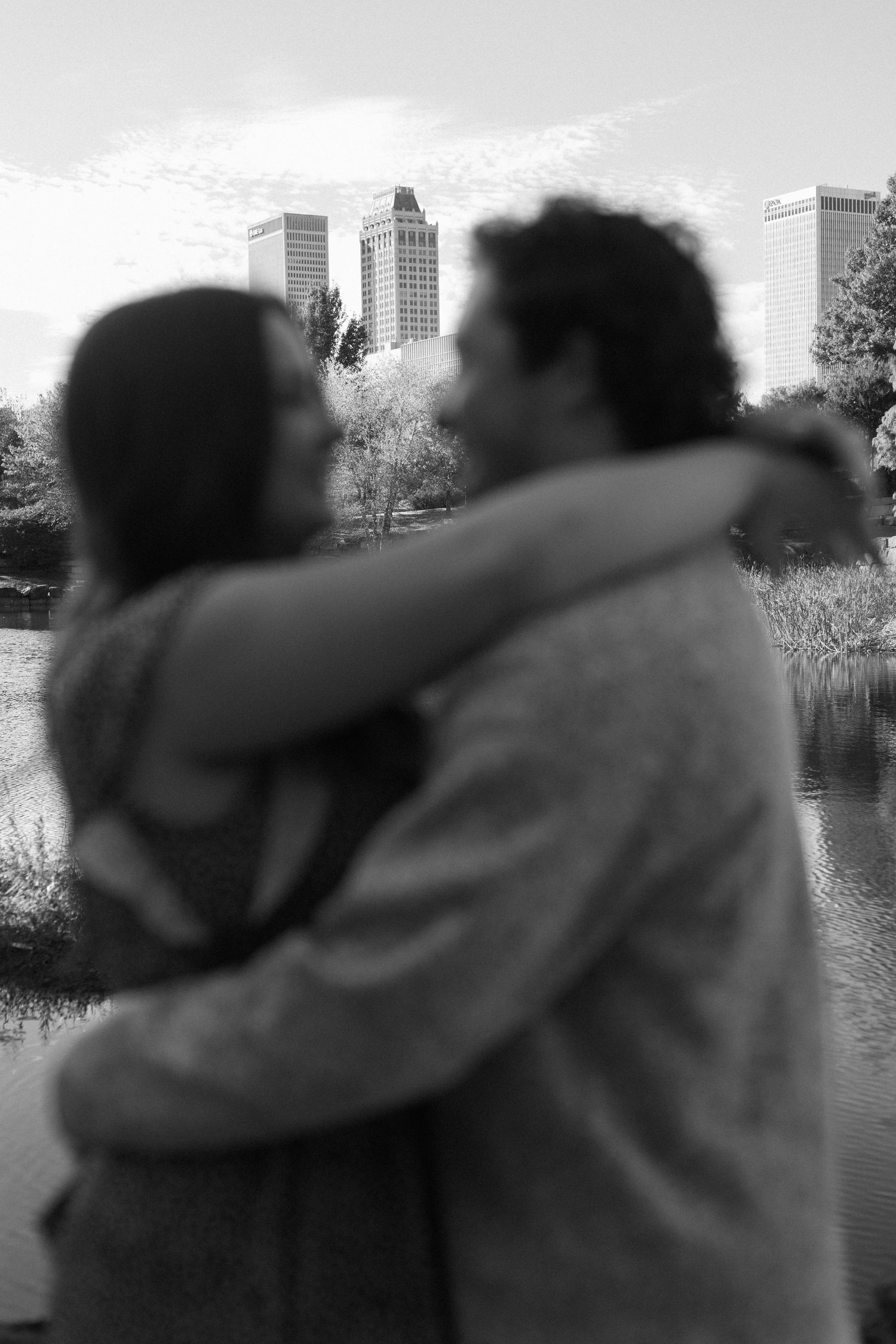Silhouetted couple embraces against a blurred cityscape and lake background.