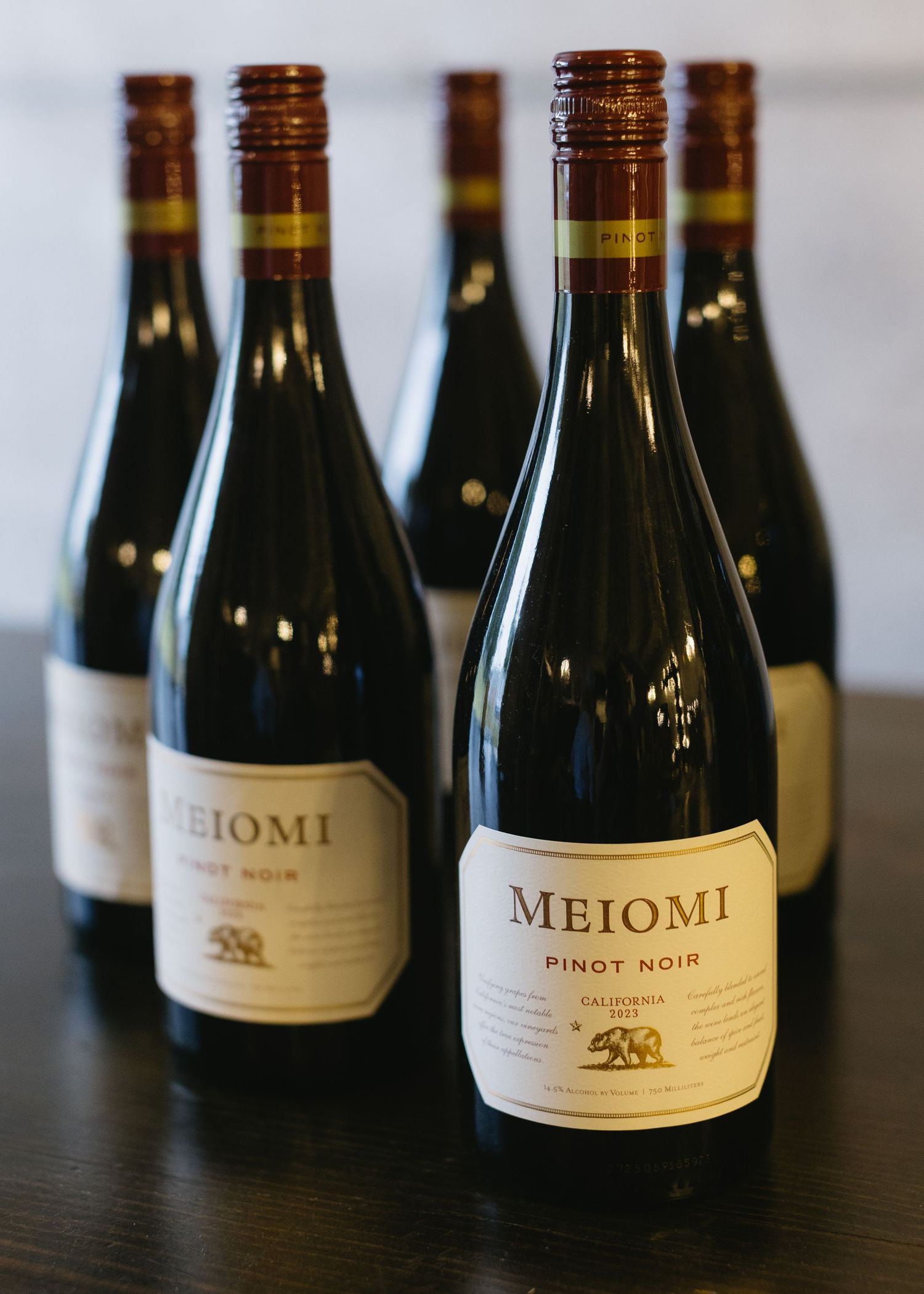Row of Meiomi wine bottles displayed on a dark surface at an event.
