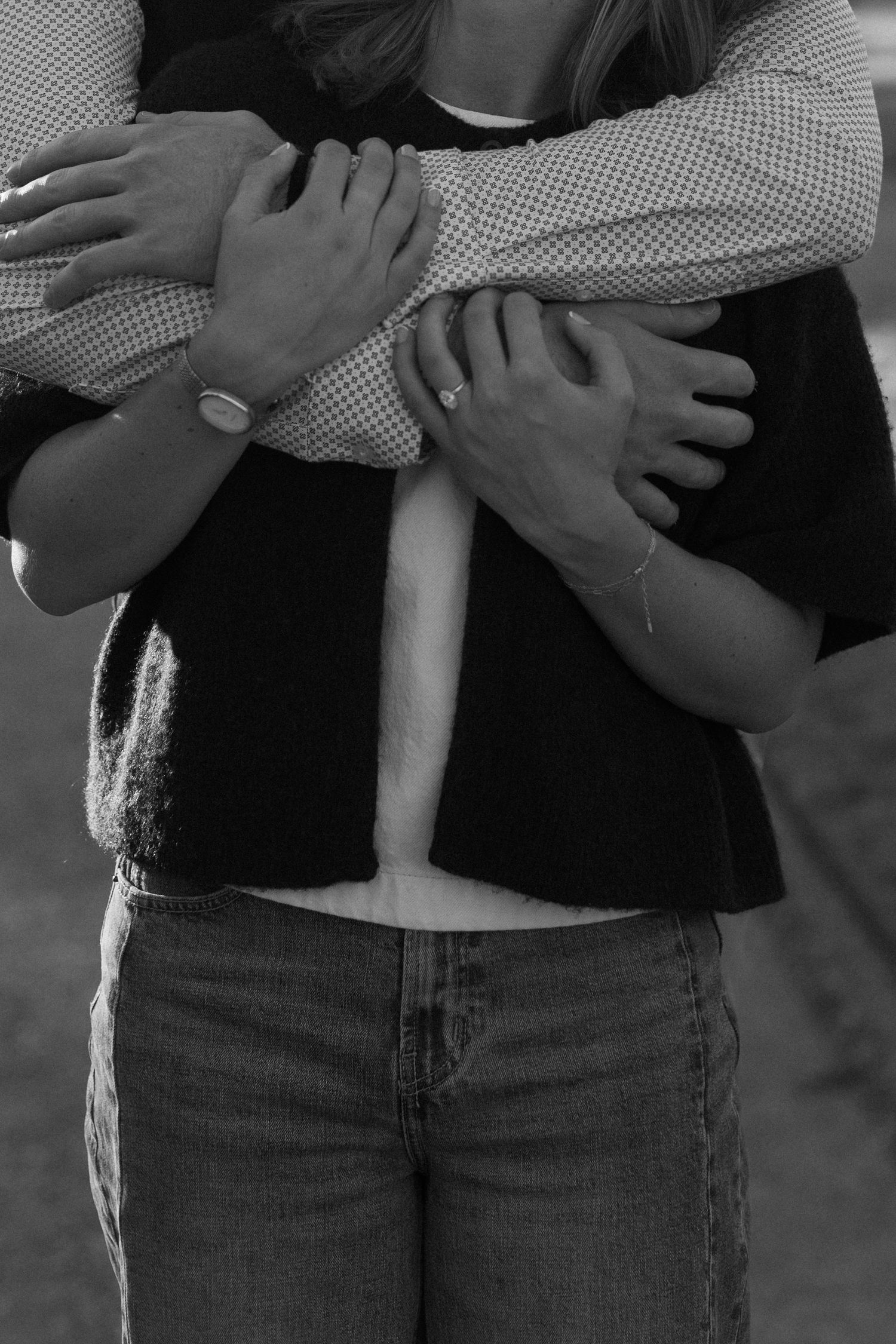 Close-up of two people embracing, wearing casual clothes in black and white.