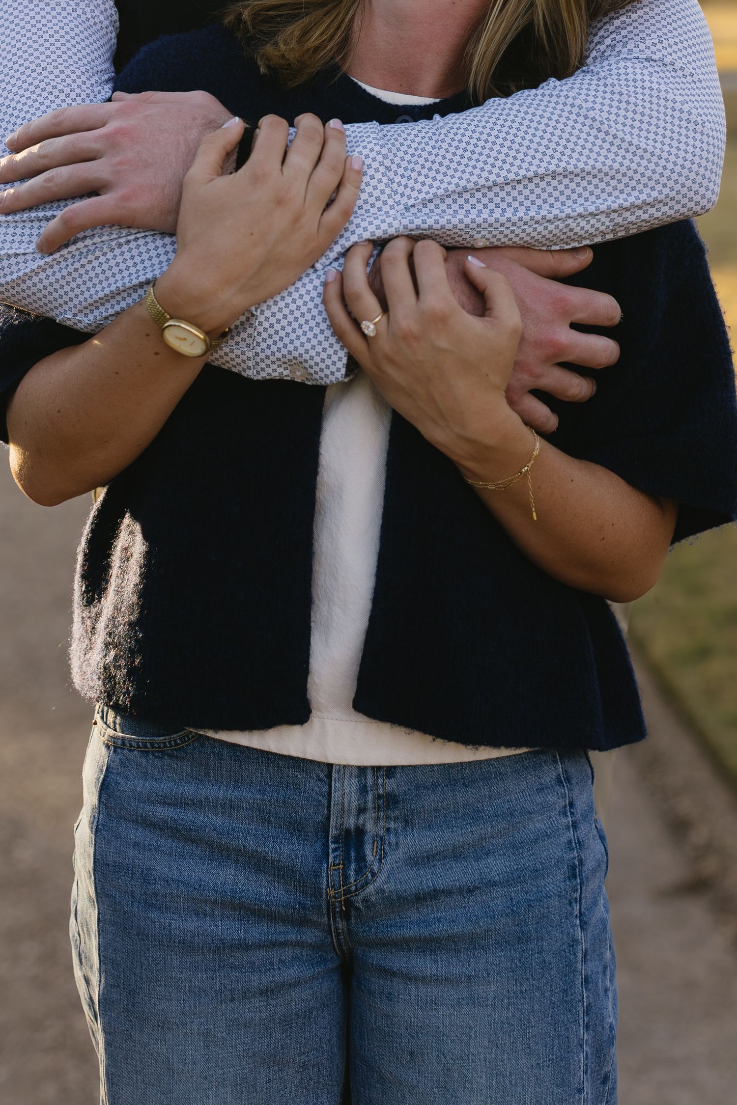 Close-up of an embrace showing blue jeans and a checkered shirt sleeve.