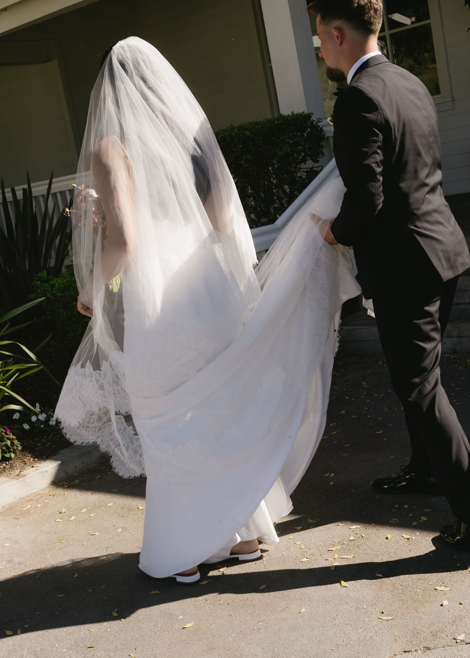 Sequence showing bride's flowing white dress and veil movement outdoors.