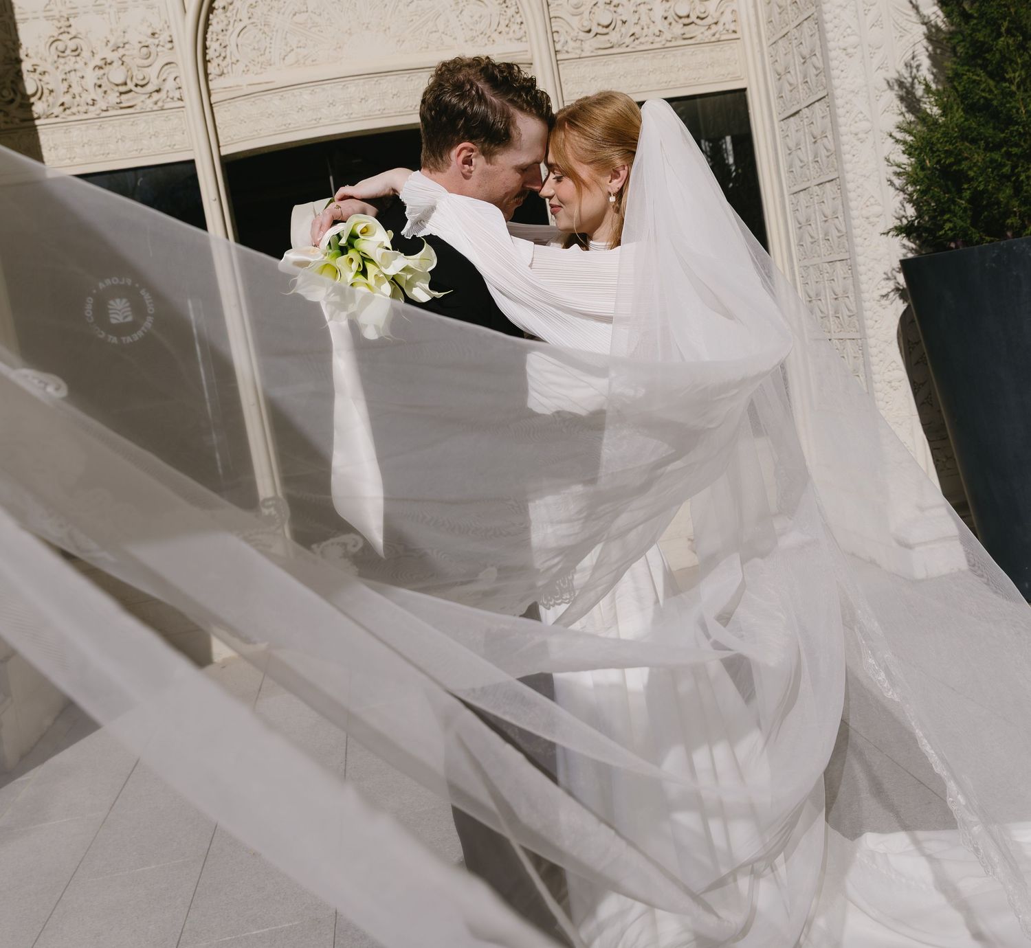 A flowing white wedding dress train spreads across a light colored floor.