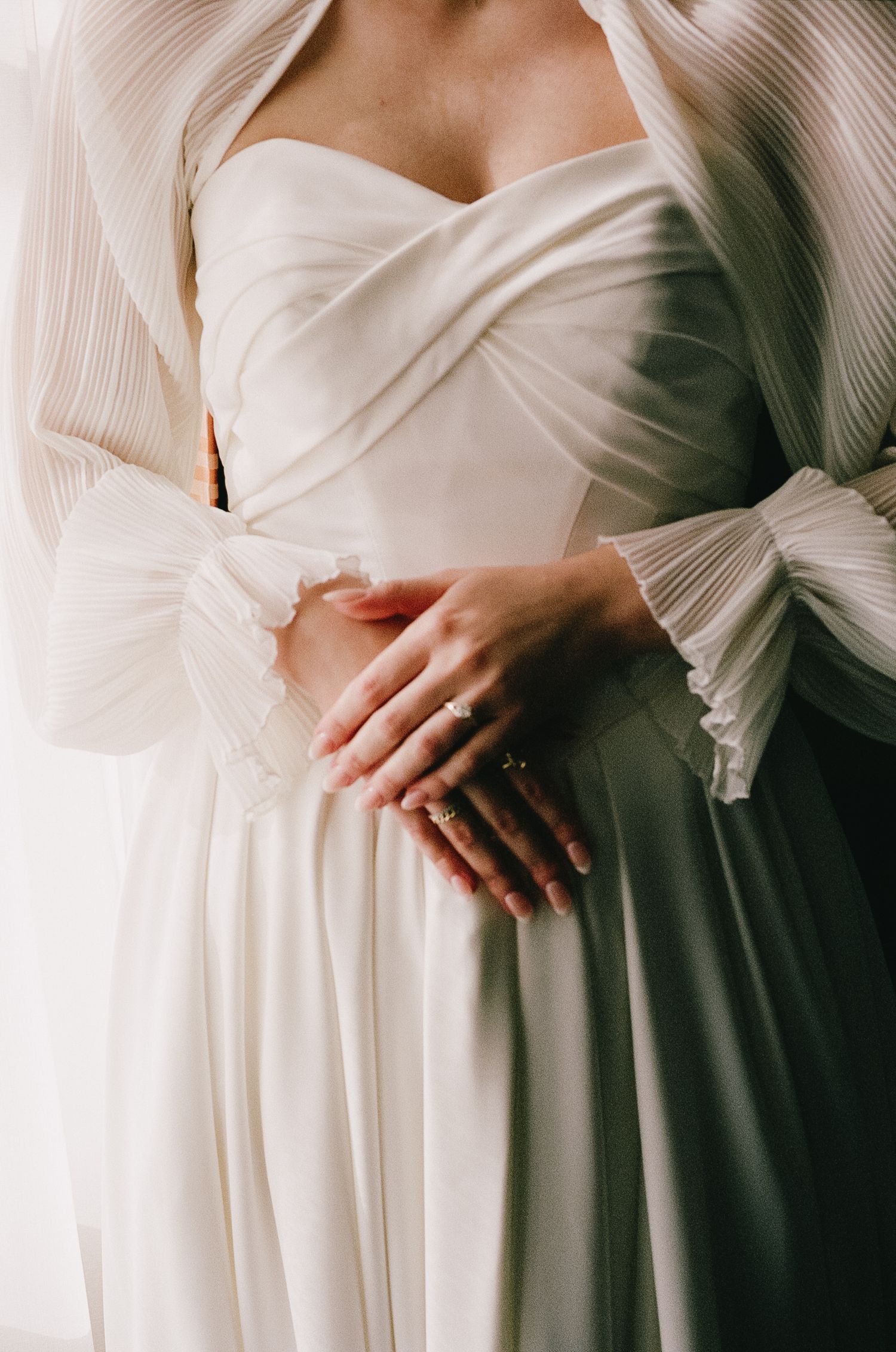 Close-up details of a white wedding dress with pleated fabric and elegant draping.
