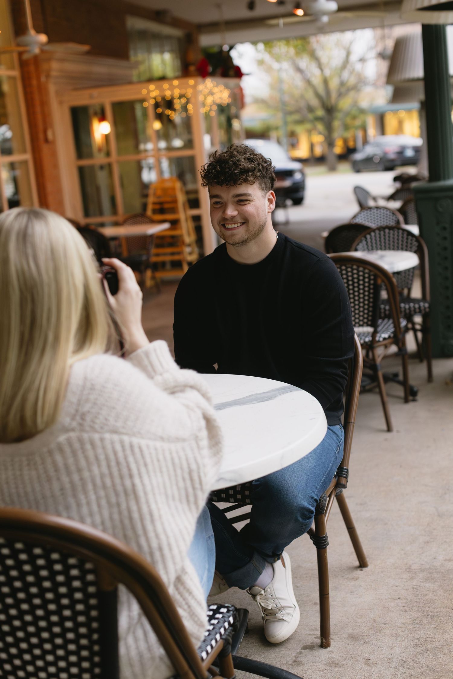 Couple sharing candid moments while seated at an outdoor cafe patio.