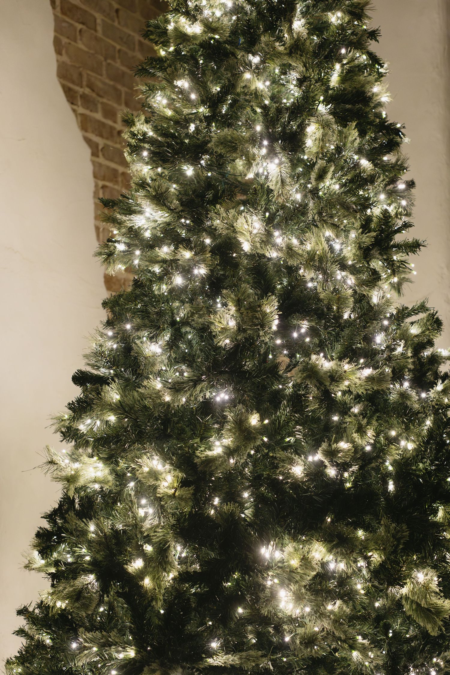 A brightly lit Christmas tree with white lights illuminates a corner of a room.