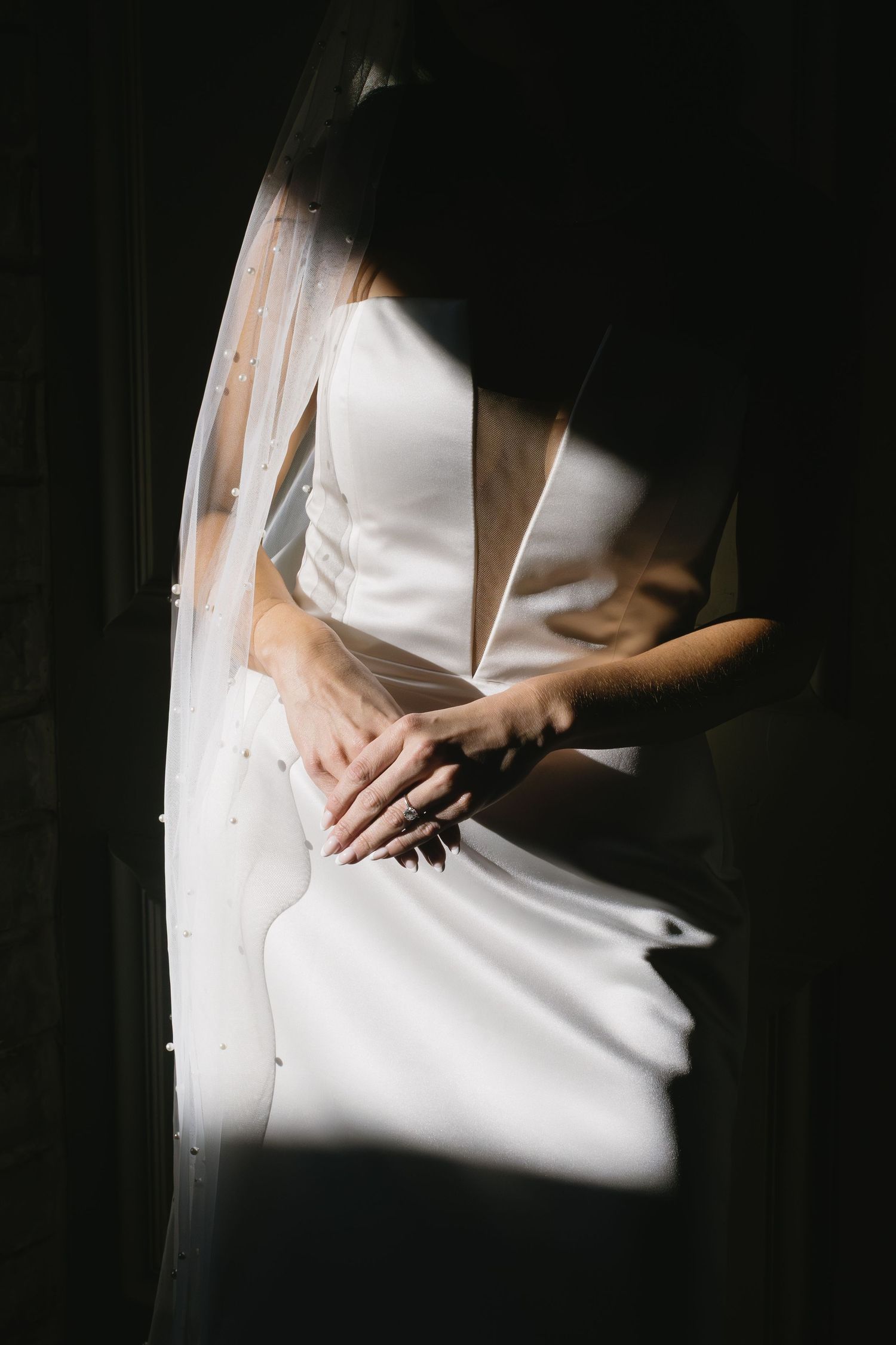 Artistic shadow play photograph of white wedding dress in dramatic lighting.