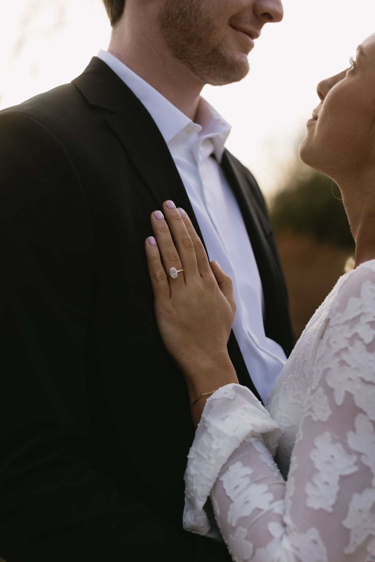 Intimate close-up of couple in formal wear with lace sleeve details.