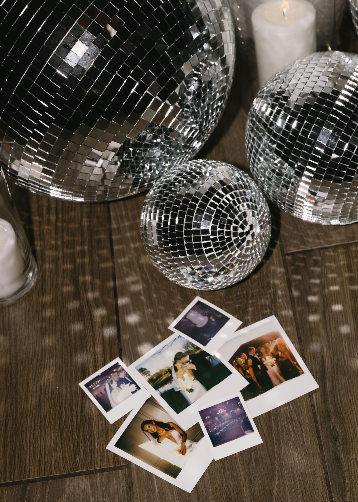 Disco balls casting speckled light patterns with vintage polaroid photos scattered on wooden floor.