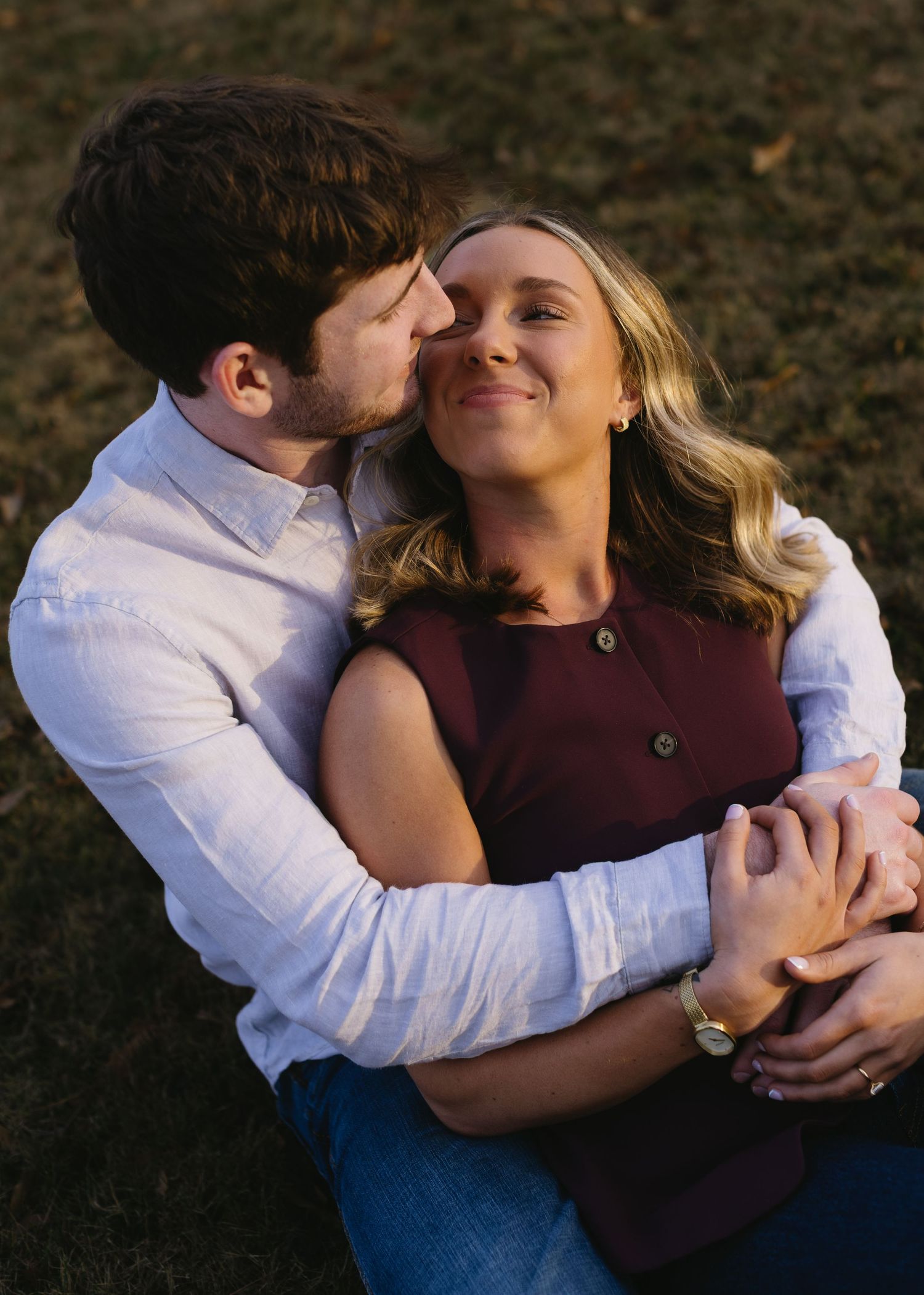 An intimate moment between a couple embracing in casual attire outdoors.