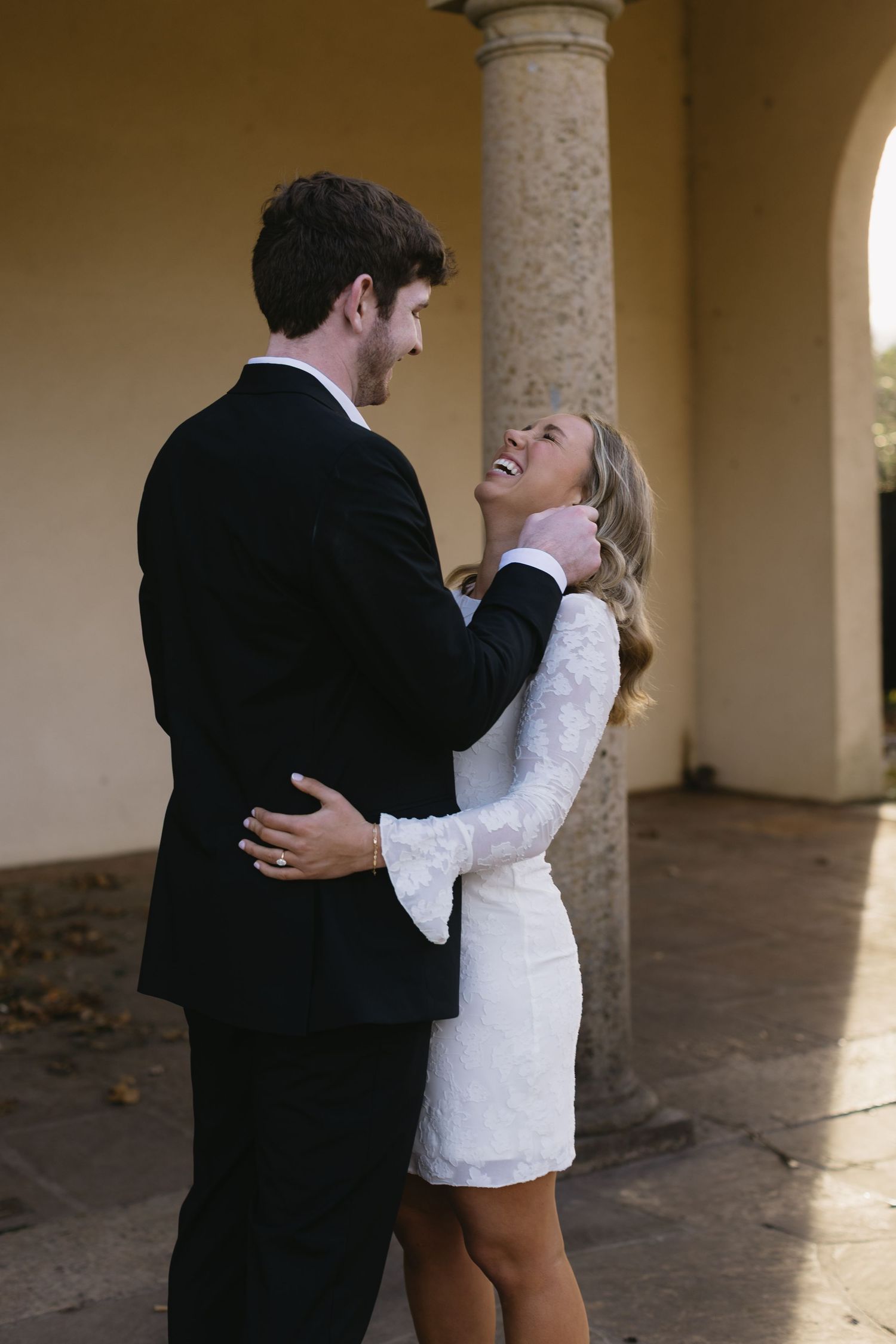 A romantic moment shared between a couple under stone archways with dramatic lighting.