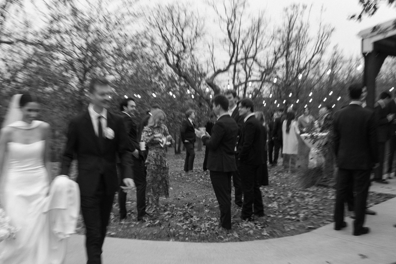 Black and white photo of wedding guests gathered outdoors for celebration.