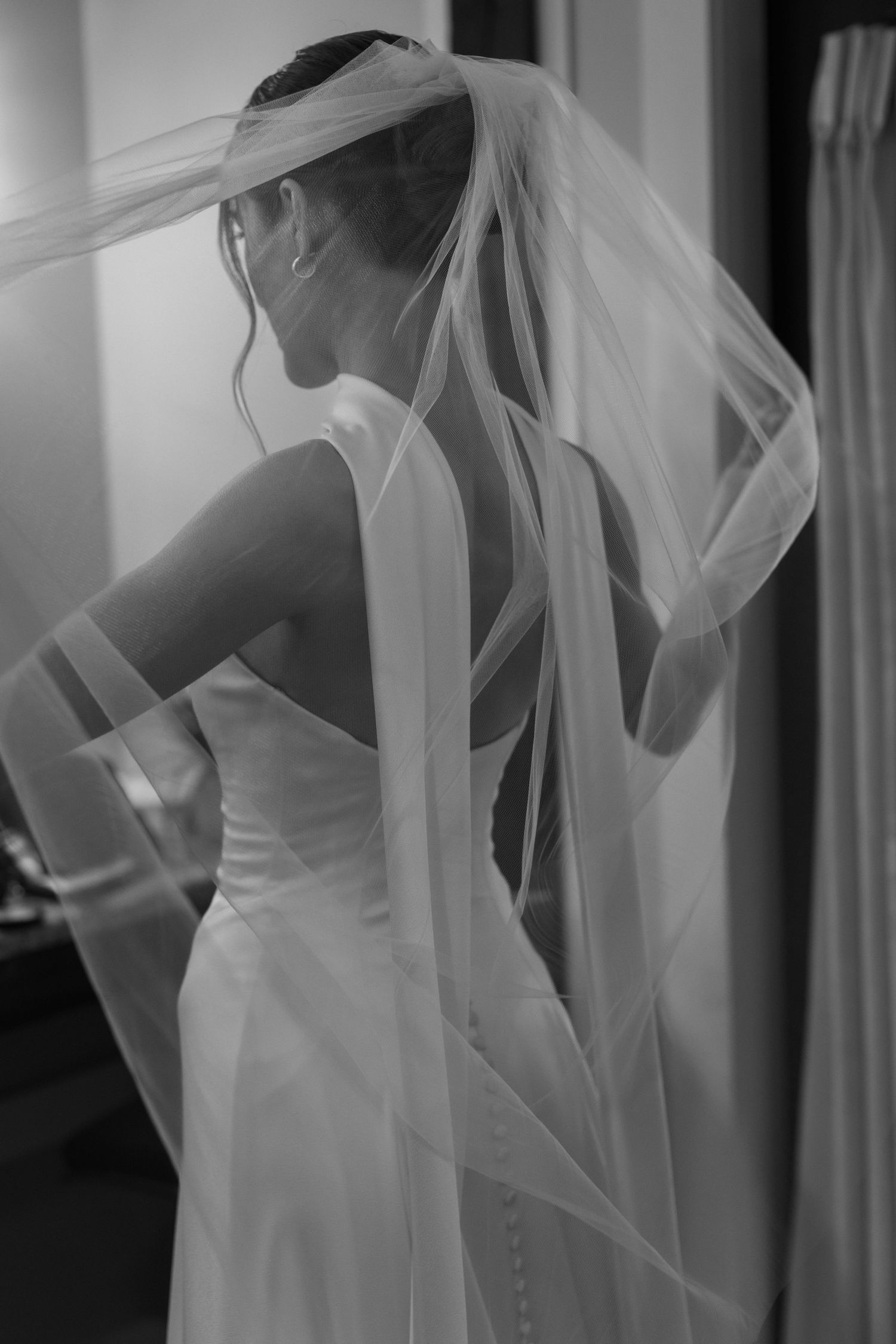 Artistic black and white photo of flowing wedding veil and dress details.
