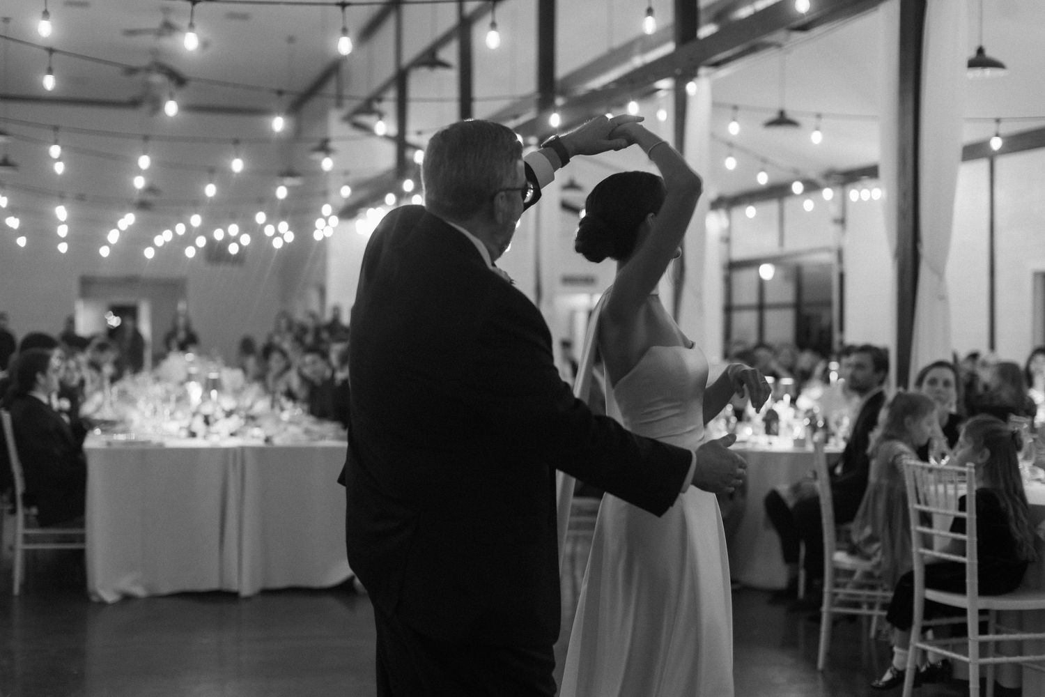 Wedding reception venue with tables set up and string lights creating a romantic atmosphere.